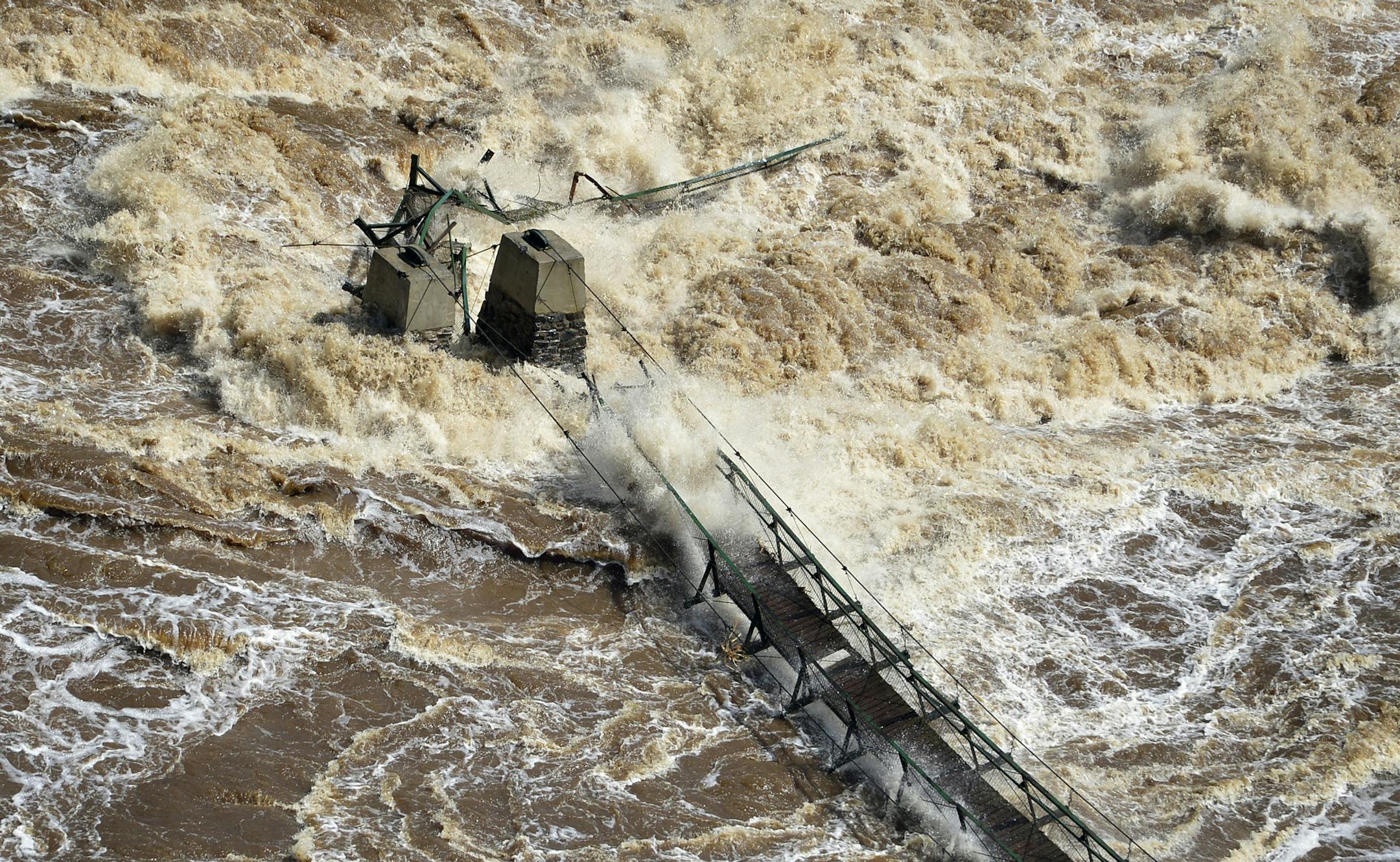 Water from the St.Louis River as it flows through Jay Cooke State Park in Minnesota rips out the swinging bridge in the park, June 21, 2012.