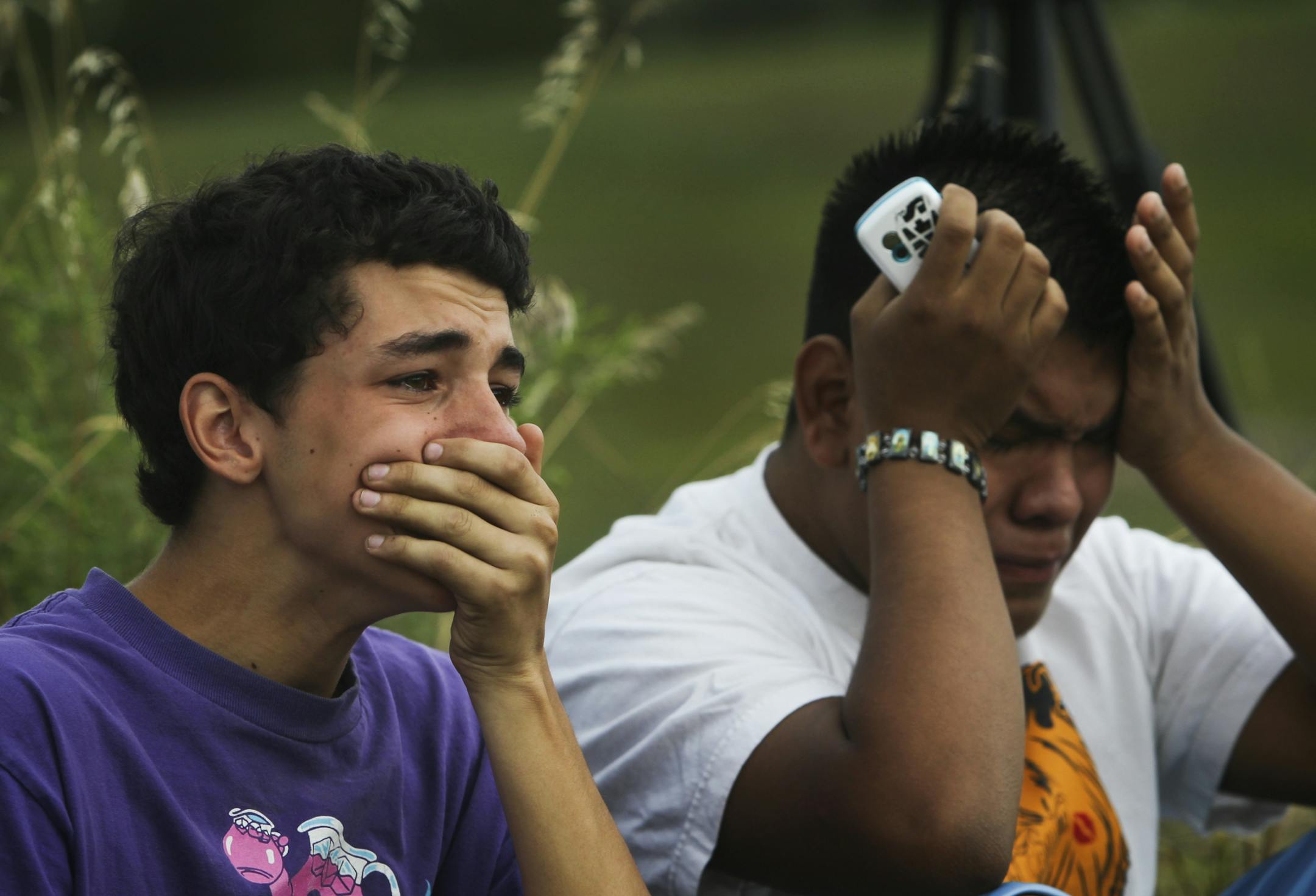 Classmates and friends of Frederick J. Alexander, 16, of Burnsville, and Alesha K. Roehl, 17, of Northfield, who were killed in a car accident Tuesday afternoon after the car five of them were riding in sped off a Burnsville frontage road, rolled over and wound up on Interstate 35, gathered near the crash site Wednesday, August 22, 2012, in Burnsville, MN. Among them were Alfredo Cruz, right to left, and Kyle Devery. "Fred was just Fred," Cruz said through tears, recalling his friend. "No matter