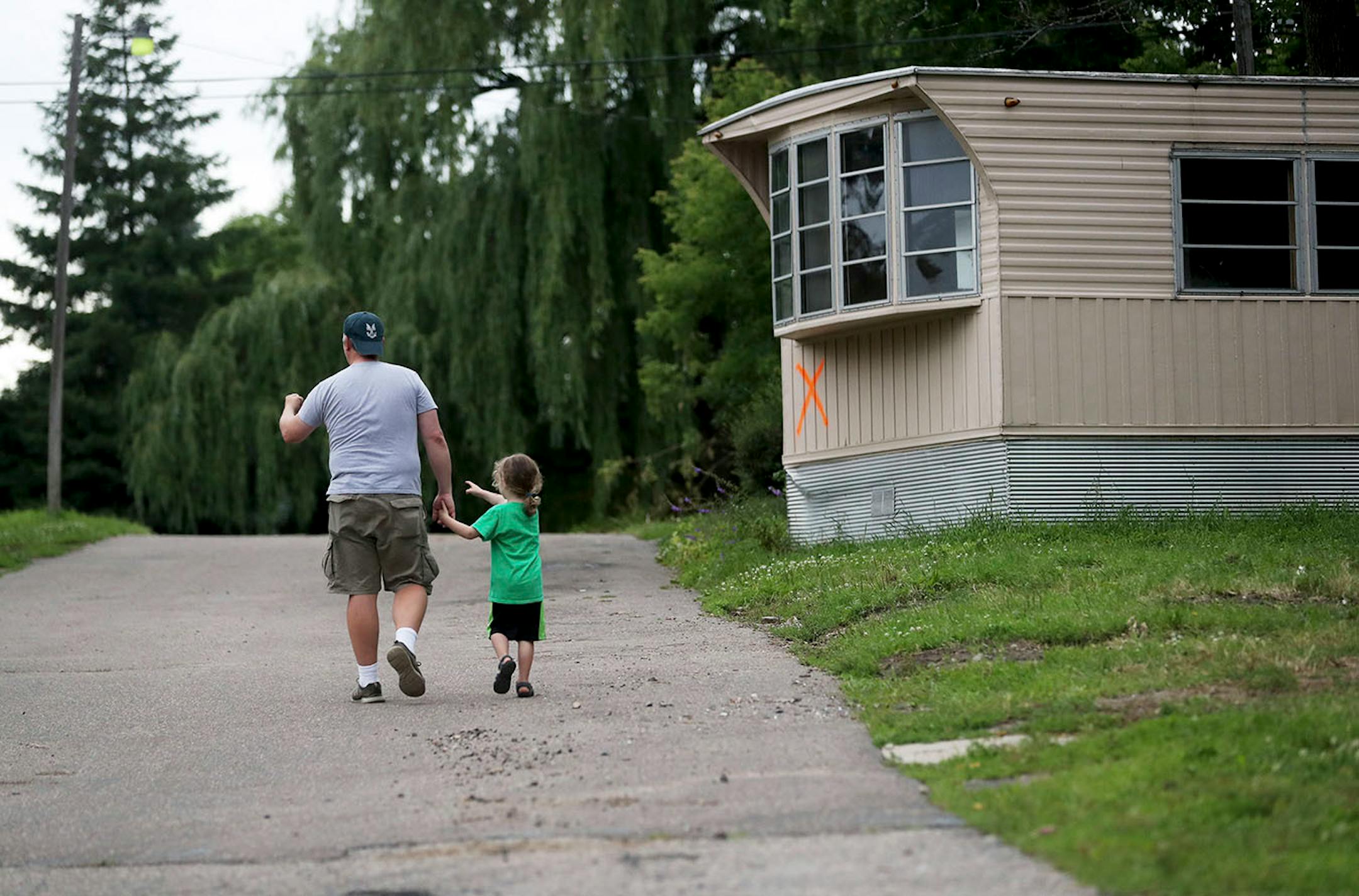 Volunteer Brian Caines of St. Anthony walks with his son Errol, 5, as they survey the Lowry Grove mobile home park for a final time Friday, June 30, 2017, in St. Anthony, MN. Lowry Grove closed it's gate and all residents had to be gone by 12 midnight the following day, the space slated to be redeveloped into multiple-family housing. The Caines family had been helping residents moving from Lowry Grove.