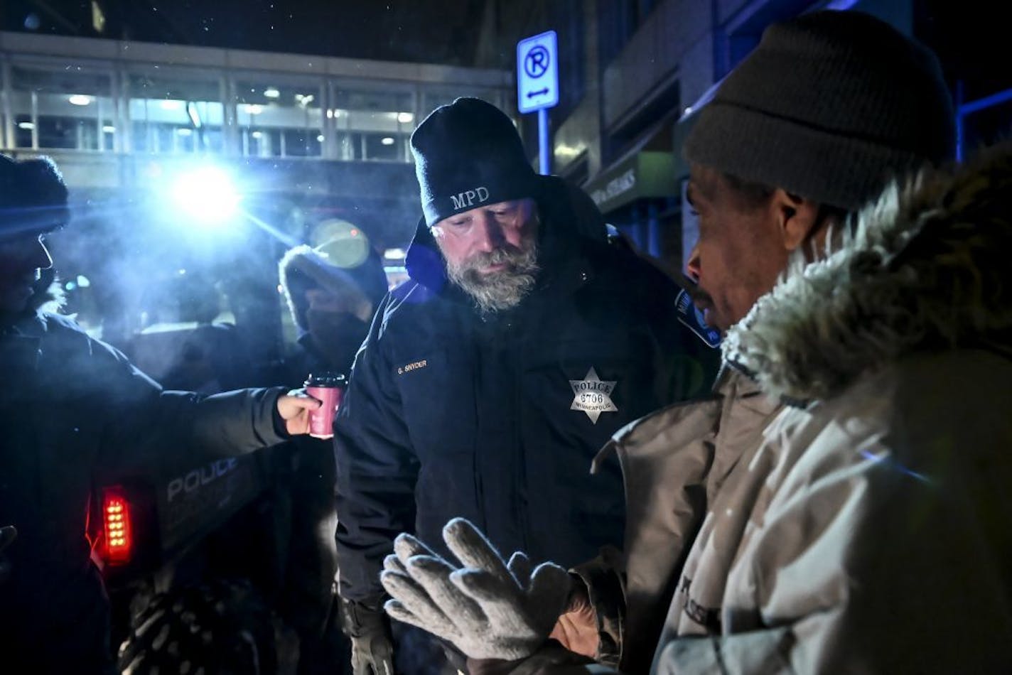 Minneapolis Police Sgt. Grant Snyder, center, and Pastor John Steger, with Grace In The City Church, far left, gave out hats, scarves, gloves and hot chocolate to homeless people enduring the dangerous cold in downtown Minneapolis Tuesday night.