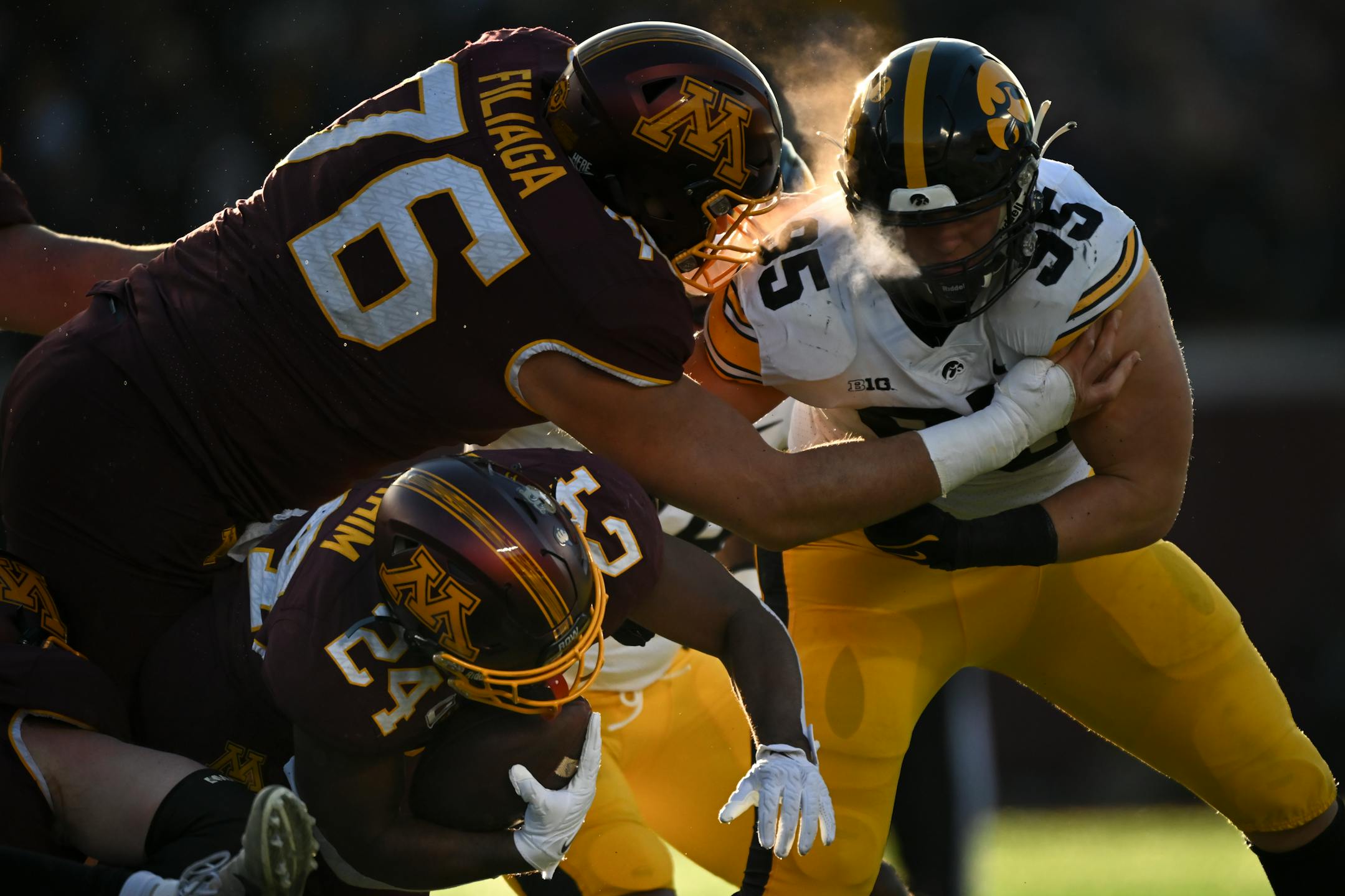 Minnesota Gophers running back Mohamed Ibrahim (24) falls to the turf as offensive lineman Chuck Filiaga (76) blocks Iowa Hawkeyes defensive lineman Aaron Graves (95) during the first half.