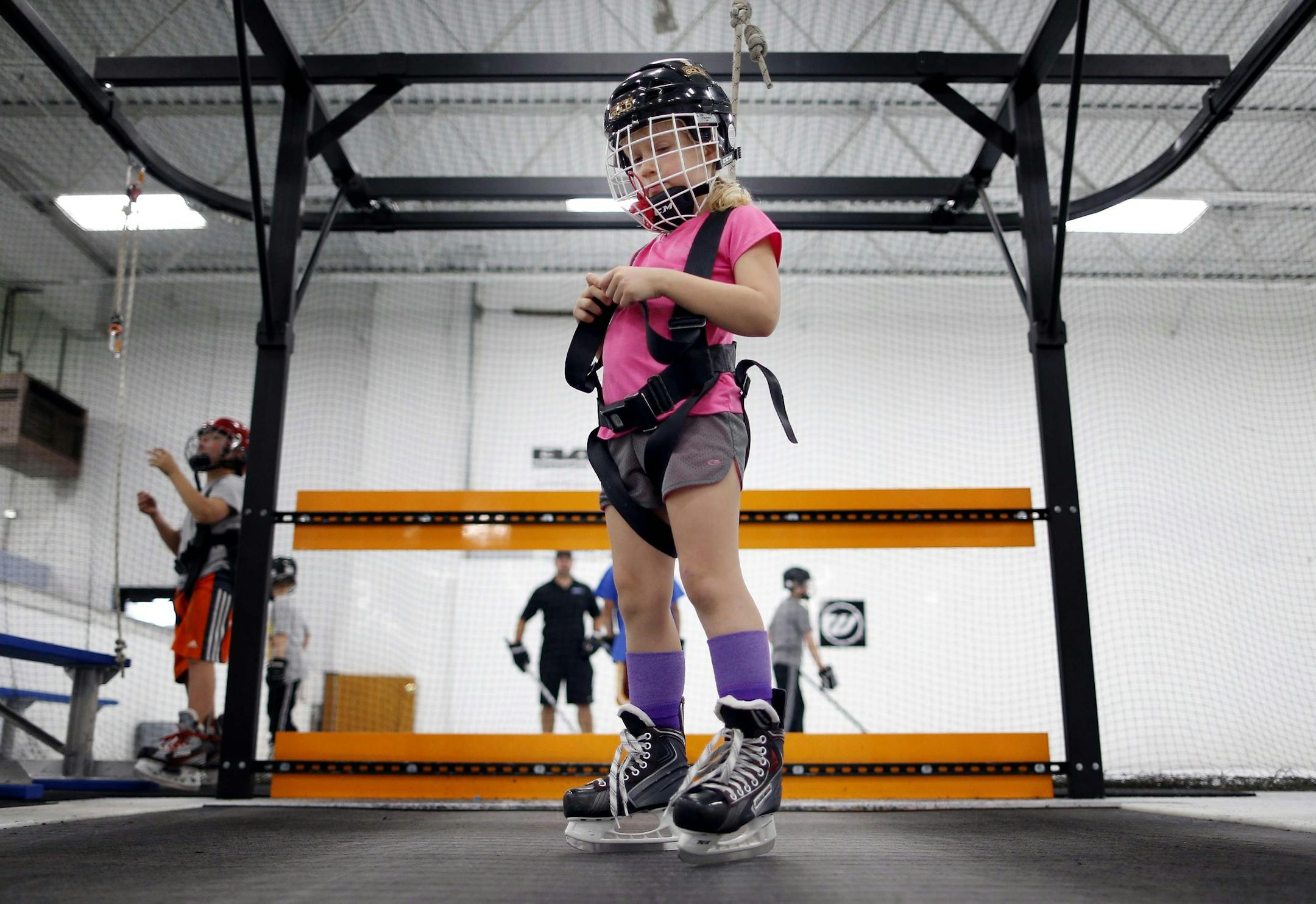 Sara Woll, 7, waited for her turn on a treadmill to test her skating skills at 1st Athlete training center in Edina. Her parents, Jon and Molly, have her playing on two hockey teams this fall. Yet the Wolls sometimes wonder: Are they creating opportunities for improvement for their daughter or pushing her too hard? Costs are also a factor, including $68 a month at 1st Athlete, $250 to play with the Minneapolis Storm and $400 to replace stolen hockey gear.