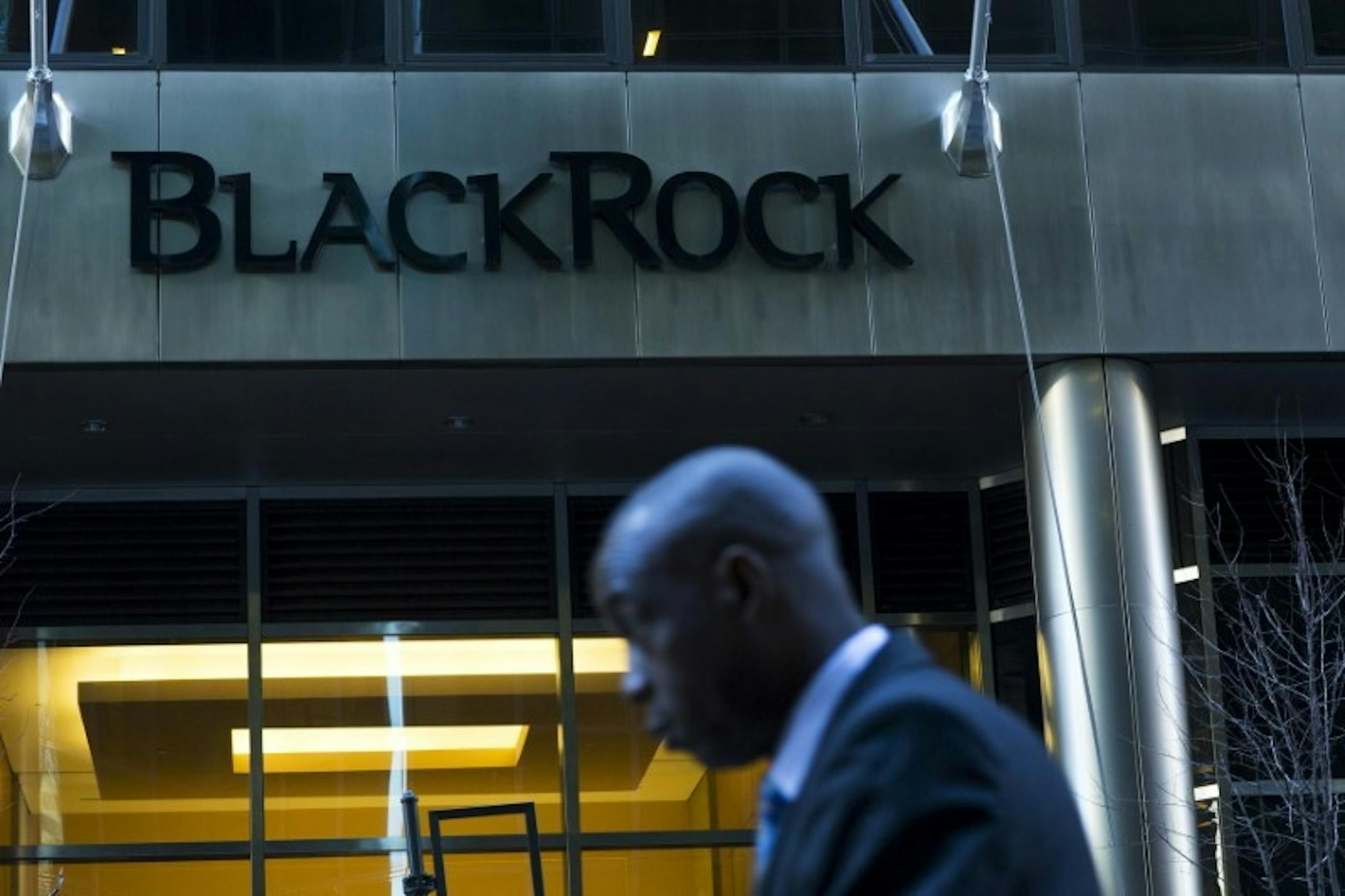 A man walks next to a BlackRock sign pictured in the Manhattan borough of New York, October 11, 2015. REUTERS/Eduardo Munoz