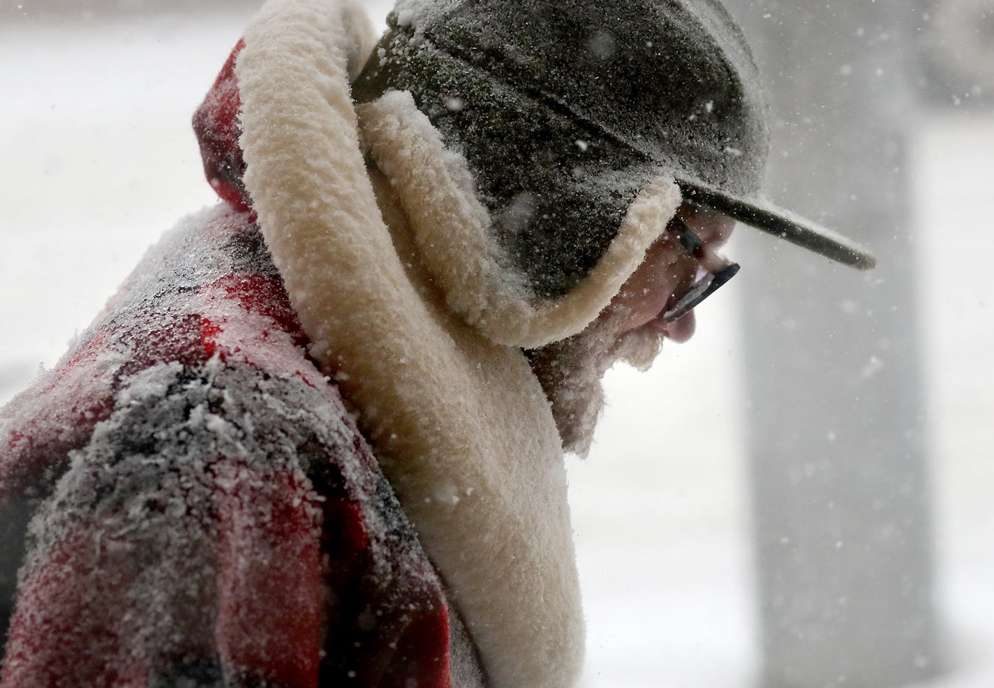 A pedestrian is caked in snow while walking along Lake St. E. near 10th Ave. in a blizzard Saturday, April 14, 2018, in Minneapolis, MN.