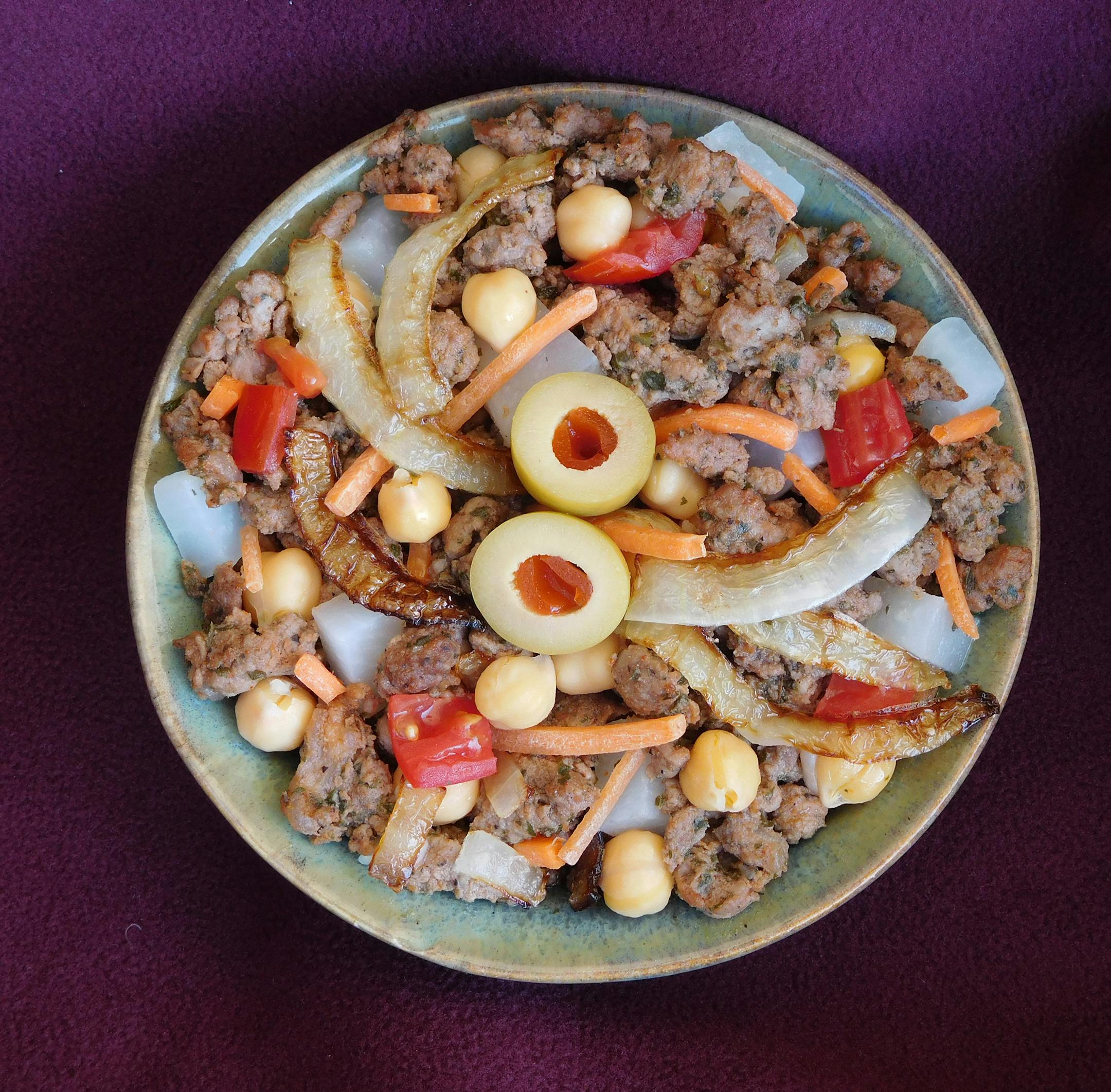 Moroccan Sausage Bowl: Coarse ground beef and lamb sausage seasoned with herbs, sweet spices and a hint of red pepper, cooked with carrots, turnips and chick peas, and topped with sautéed onions and a green olive. At Sausage by Cynthia, located on the north side of Judson Av. between Nelson & Underwood streets.