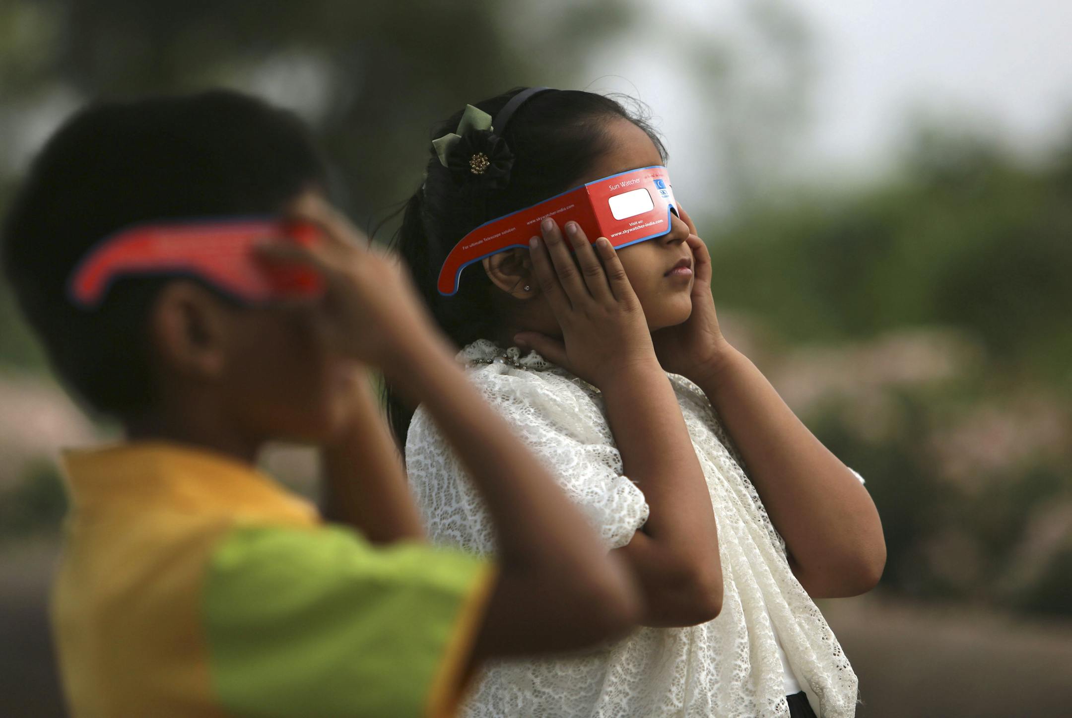 Indian children watch a partial solar eclipse in Hyderabad, India, Wednesday, March 9, 2016 Indian people in northeast and eastern coastal strip of the sub-continent viewed a partial solar eclipse as a total eclipse of the sun unfolded over Indonesia on Wednesday, briefly plunging cities into darkness and startling wildlife. (AP Photo /Mahesh Kumar A.)