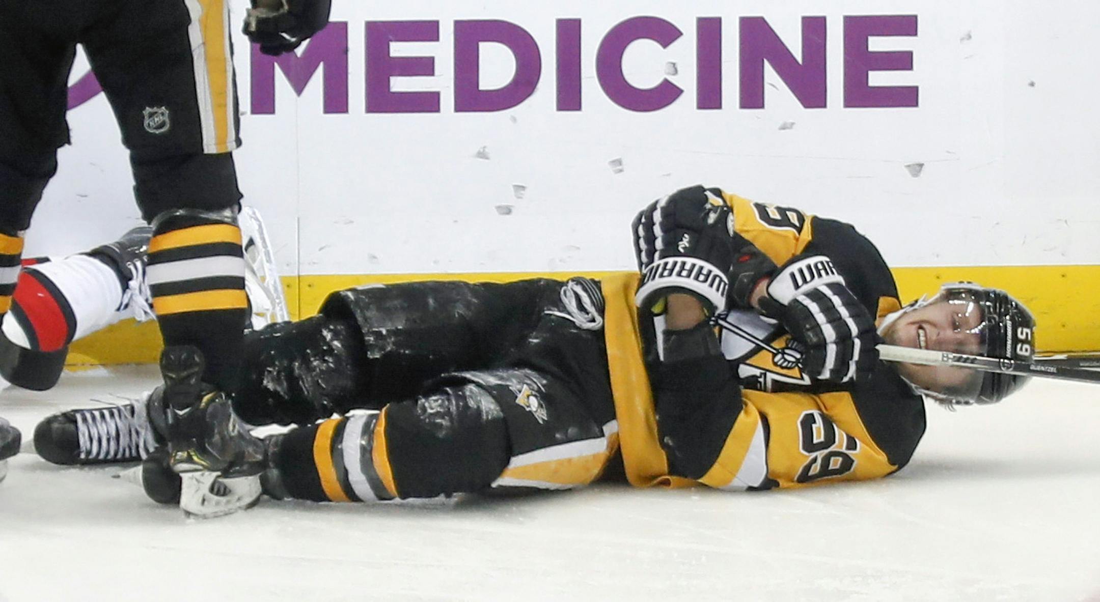 Pittsburgh Penguins' Jake Guentzel (59) rolls on the ice after being injured after scoring a goal against the Ottawa Senators during the third period of an NHL hockey game, Monday, Dec. 30, 2019, in Pittsburgh. Guentzel left the ice and did not return to the game. (AP Photo/Keith Srakocic)