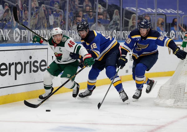 The Wild's Jared Spurgeon battles St. Louis Blues' Zach Sanford and Mackenzie MacEachern for the loose puck in the second period