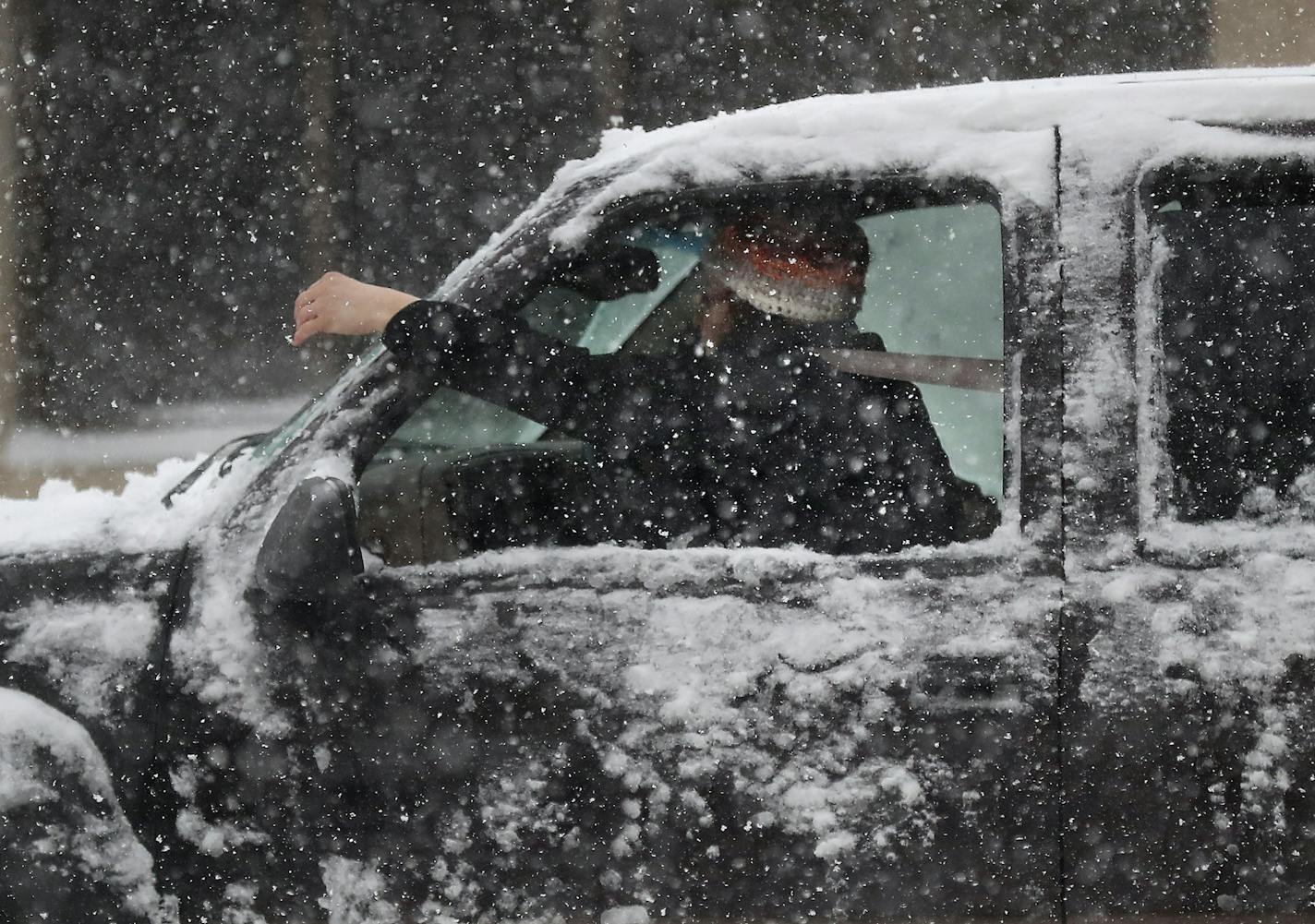 A motorist tries to clear snow from the car's windshield along Lake St. E. near 10th Ave. in a blizzard Saturday, April 14, 2018, in Minneapolis, MN.