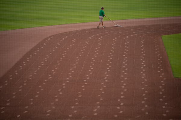 A member of the grounds crew raked the infield gravel at Hammond Stadium after a night of heavy rain in Fort Myers, Florida Wednesday, March 16, 2022.