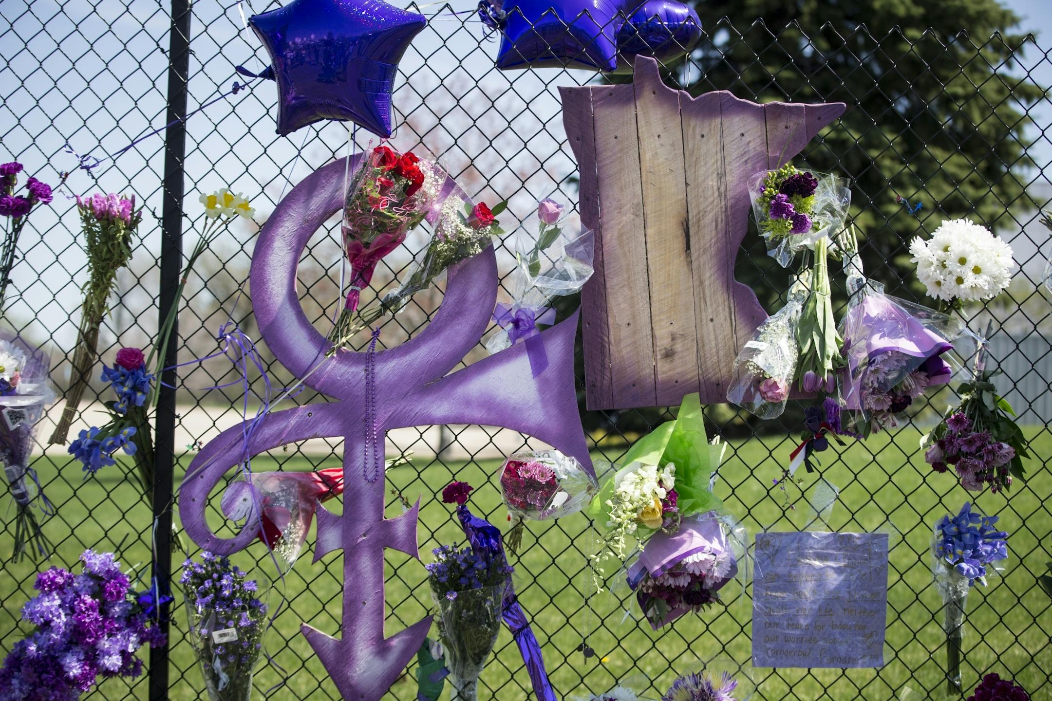 The Prince symbol and Minnesota hanging on the gate outside Prince's home at Paisley Park on Friday, April 22, 2016, in Chanhassen, Minn..
