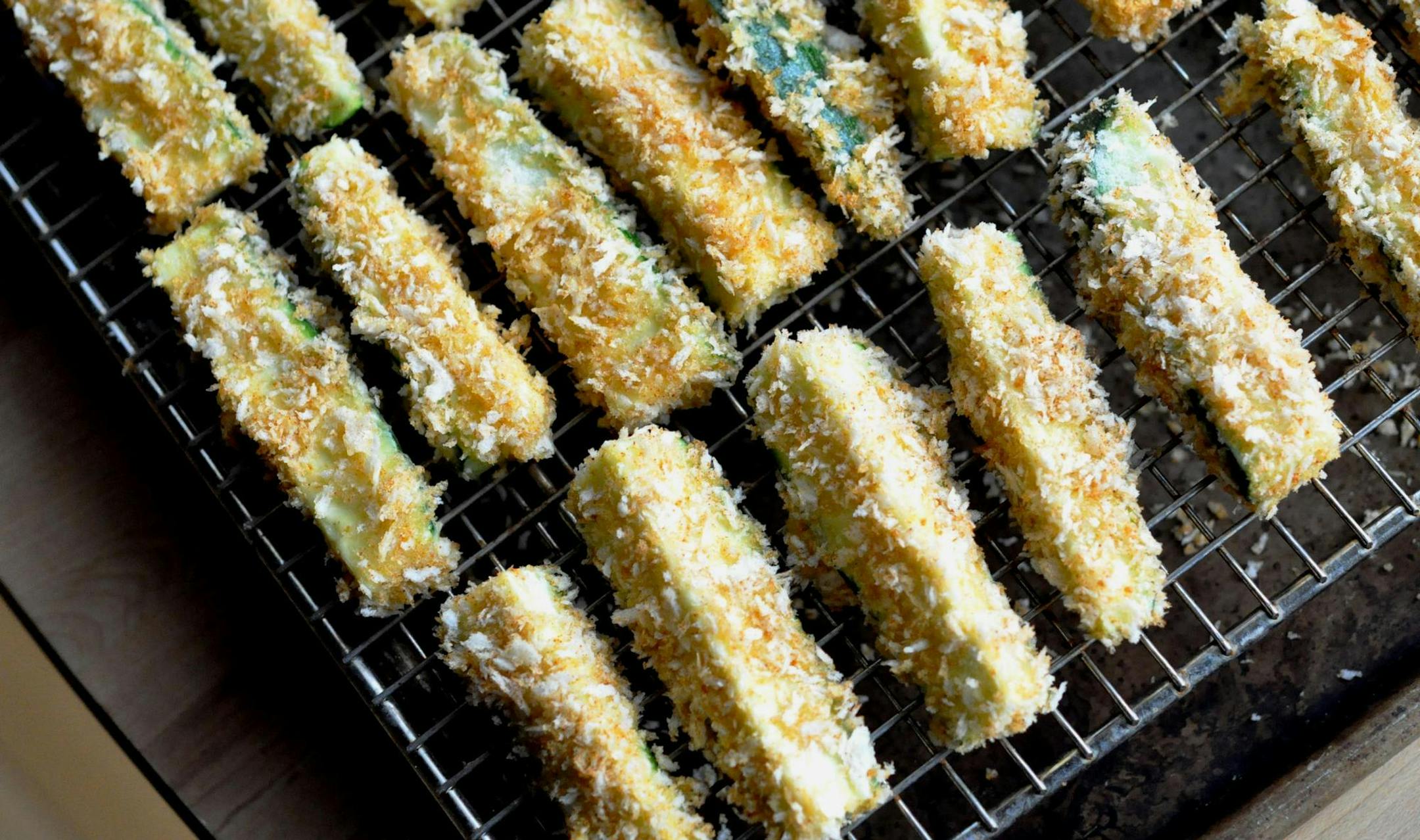 The zucchini fries are baked atop a wire rack on a baking sheet.