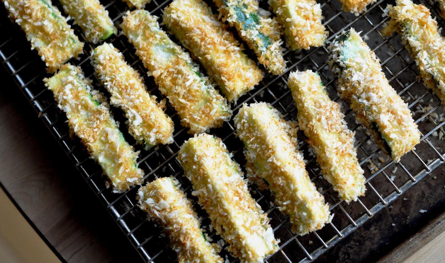 The zucchini fries are baked atop a wire rack on a baking sheet.