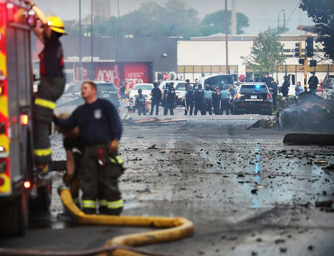 Dawn breaks after the second night of unrest in south Minneapolis, following the death Monday of unarmed George Floyd in Minneapolis Police custody. Here, Minneapolis firefighters work to put out a fire as nearby Minneapolis police stand near a Target Store that had been looted on E. Lake Street Thursday, May 28, 2020, in Minneapolis, MN.