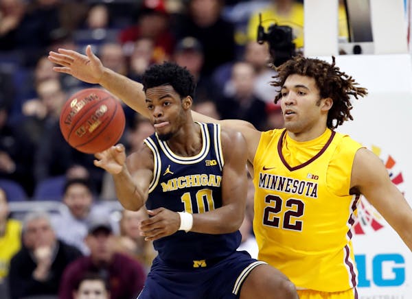 Michigan guard Derrick Walton Jr. (10) passes the ball as he is guarded by Minnesota center Reggie Lynch (22) during the first half of an NCAA college