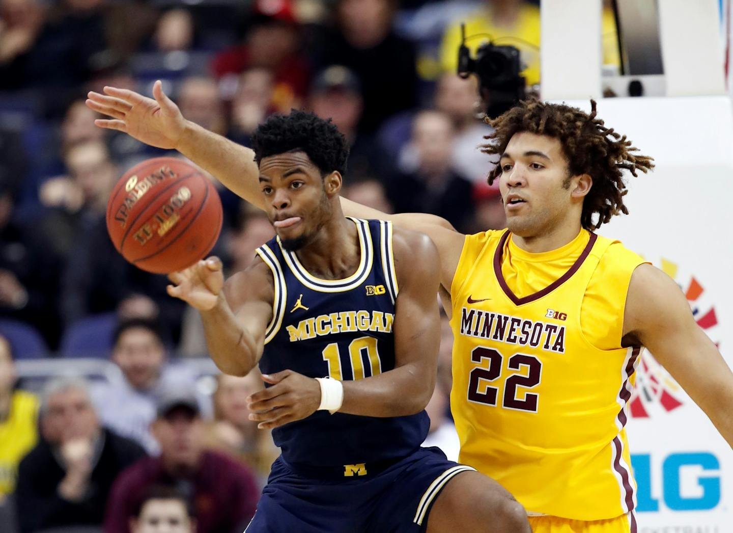 Michigan guard Derrick Walton Jr. (10) passes the ball as he is guarded by Minnesota center Reggie Lynch (22) during the first half of an NCAA college basketball game in the Big Ten tournament, Saturday, March 11, 2017, in Washington. (AP Photo/Alex Brandon)