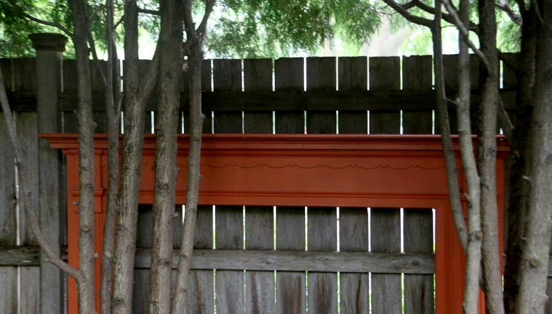 A recycled fireplace mantle was incorporated into the fence as garden art.