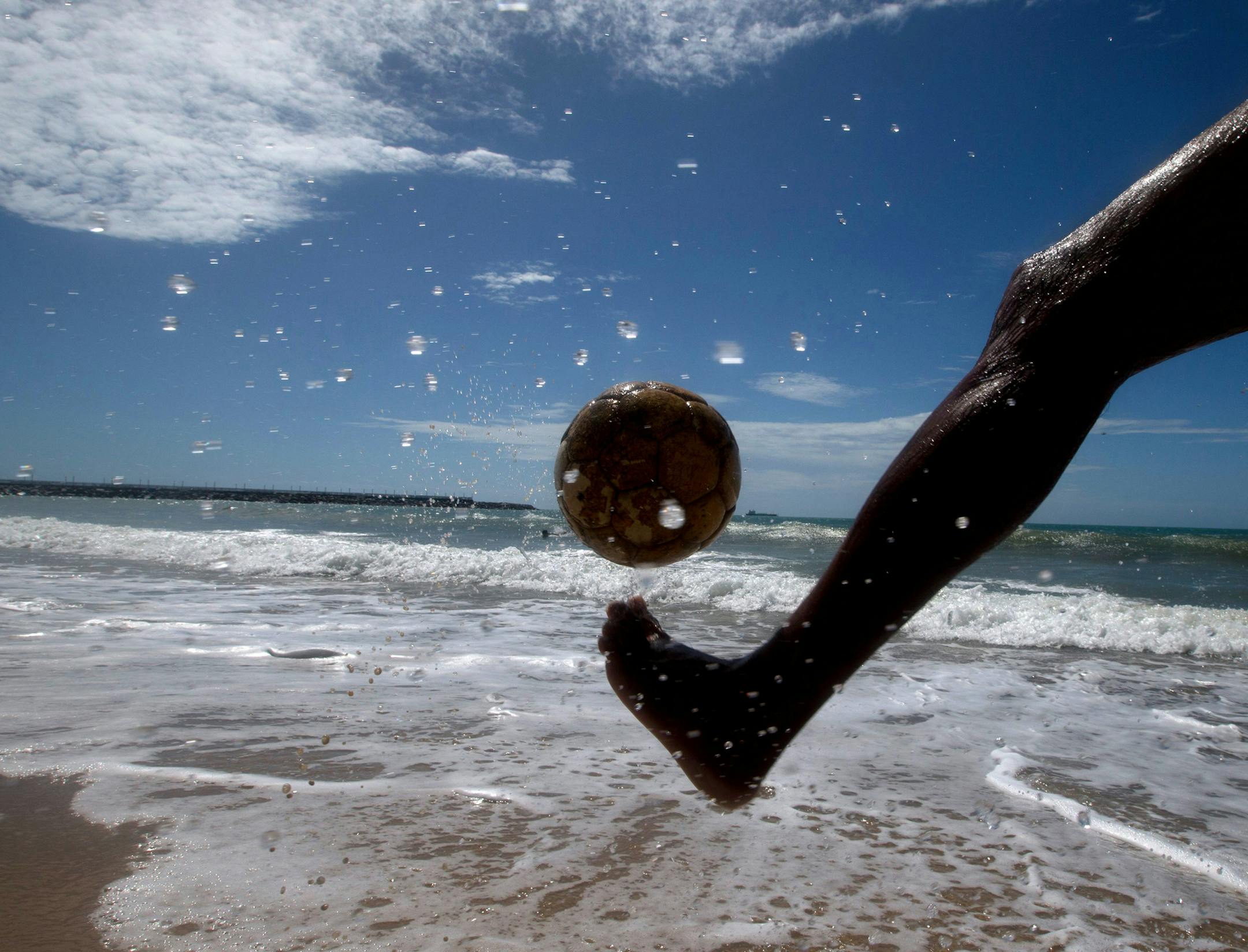 A man kicks a soccer ball on the shores of Beira Mar, in Fortaleza, Brazil, Tuesday, June 10, 2014. Soccer fans around the world are gearing up to watch the World Cup soccer tournament that kicks off in Sao Paulo, Thursday. (AP Photo/Fernando Llano)