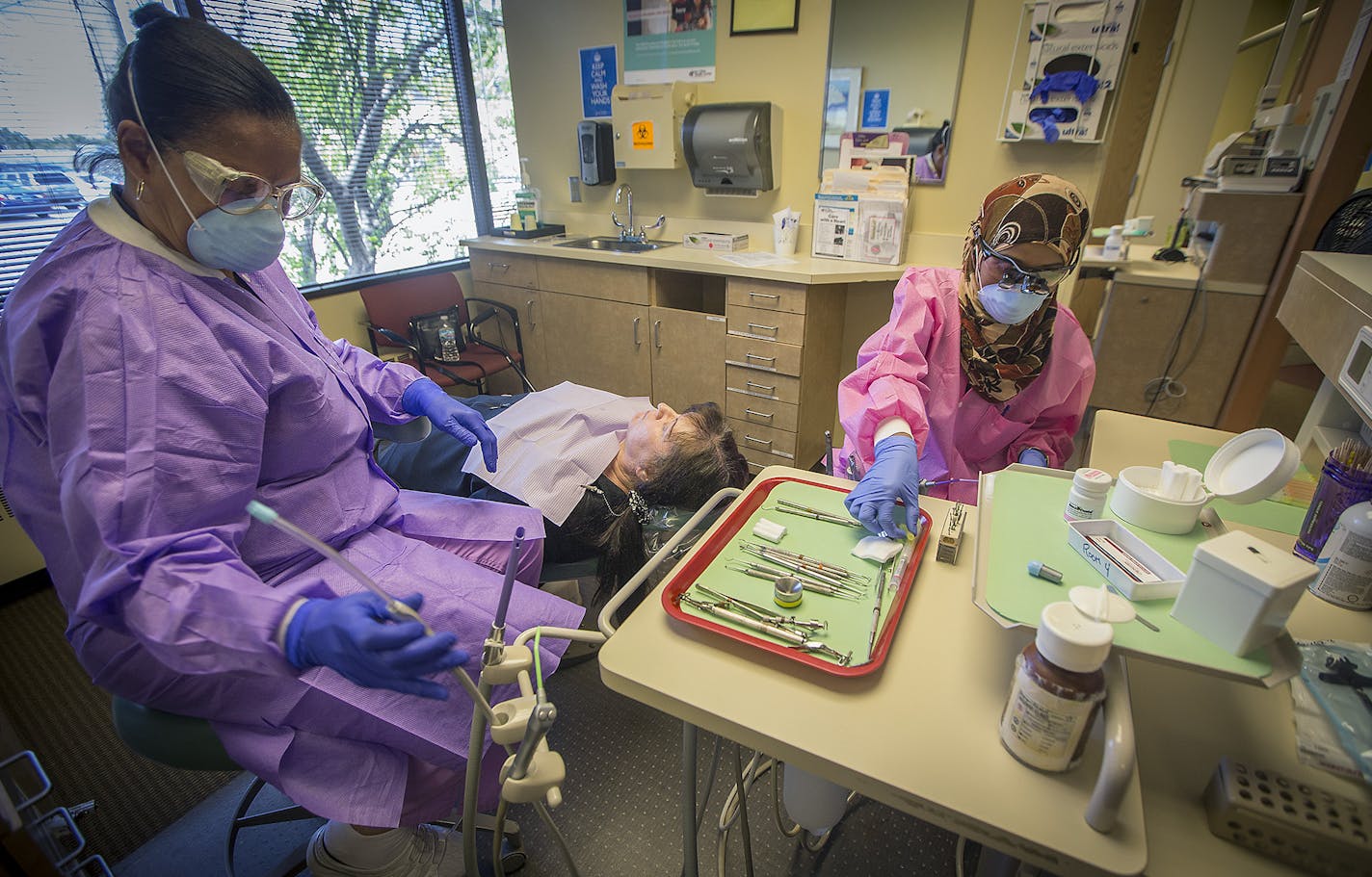 Dr. Sagal Nur, right, prepared to work on a patient at her Open Cities Health Center dental office in St. Paul on Thursday with assistant Rita Robinson.