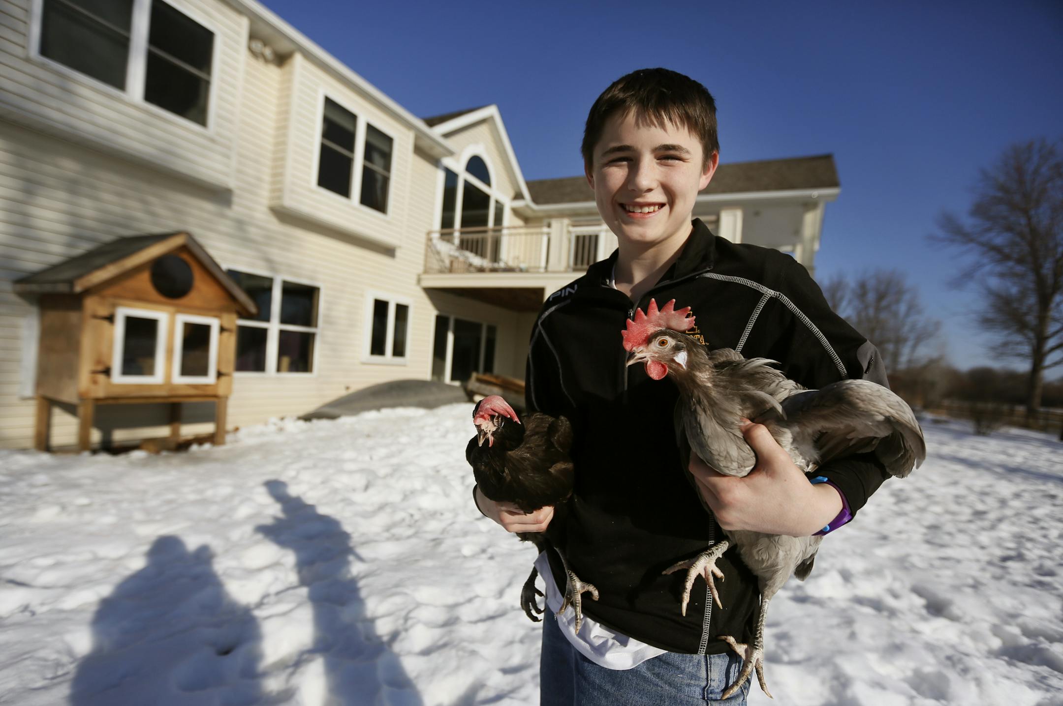 Lerew Kaas holds two of his family's three chickens outside their home in Farmington. The coop is in the background left. ] BRIAN PETERSON ‚Ä¢ brian.peterson@startribune.com Farmington, MN 2/13/2014