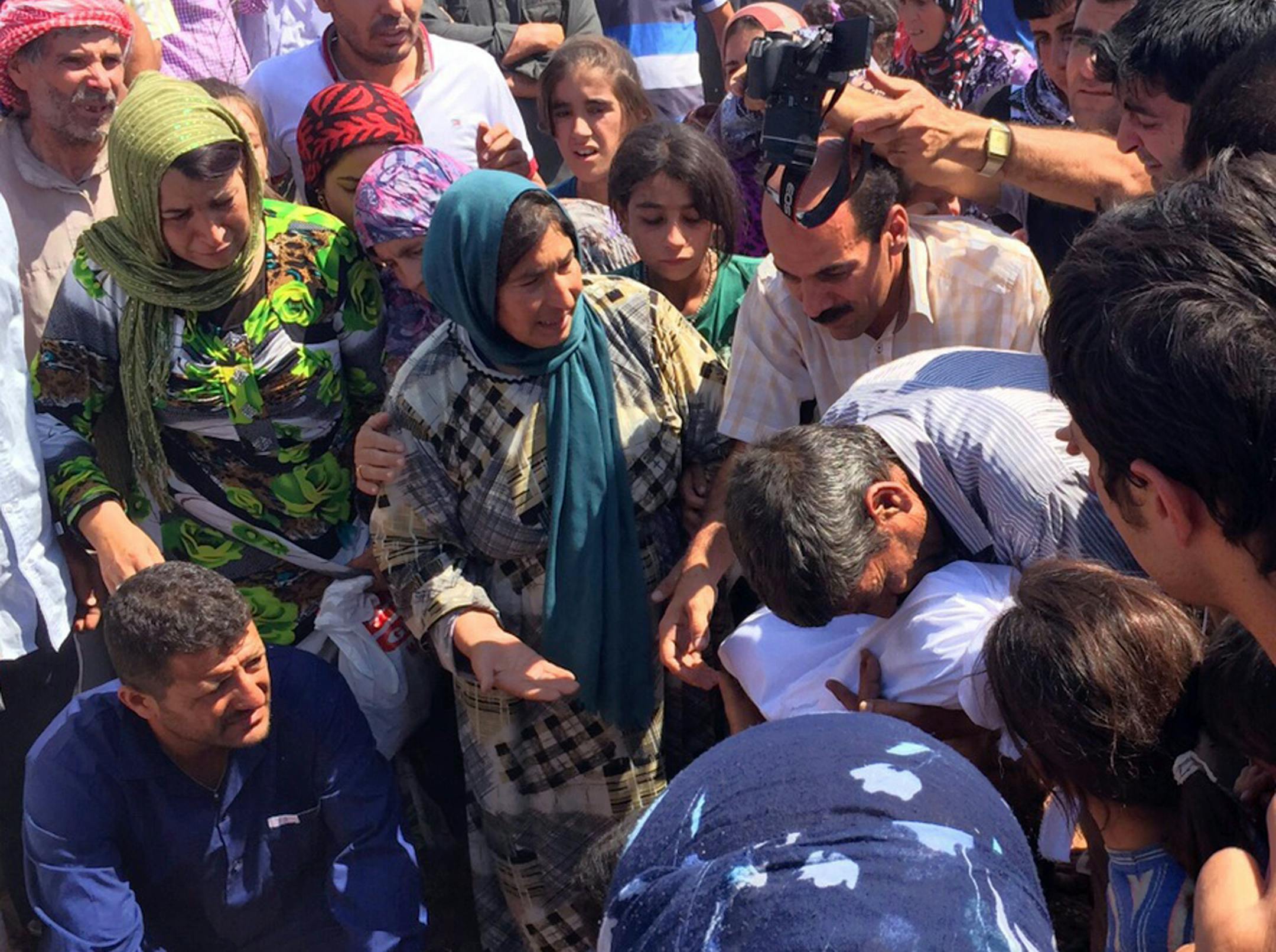 REMOVES FIRST REFERENCE TO ABDULLAH KURDI WHO IS NOT IN THE PHOTO - A relative of 3-year-old Syrian Kurdish boy Aylan Kurdi carries his body, center, during his funeral procession with his mother Rehan, and his older brother Galib, in Kobani, Syria, Friday, Sept. 4, 2015. The Syrian man who survived a capsizing during a desperate voyage from Turkey to Greece buried his wife and two sons on Friday in their hometown of Kobani, returning them to the conflict-torn Syrian Kurdish region they had fled
