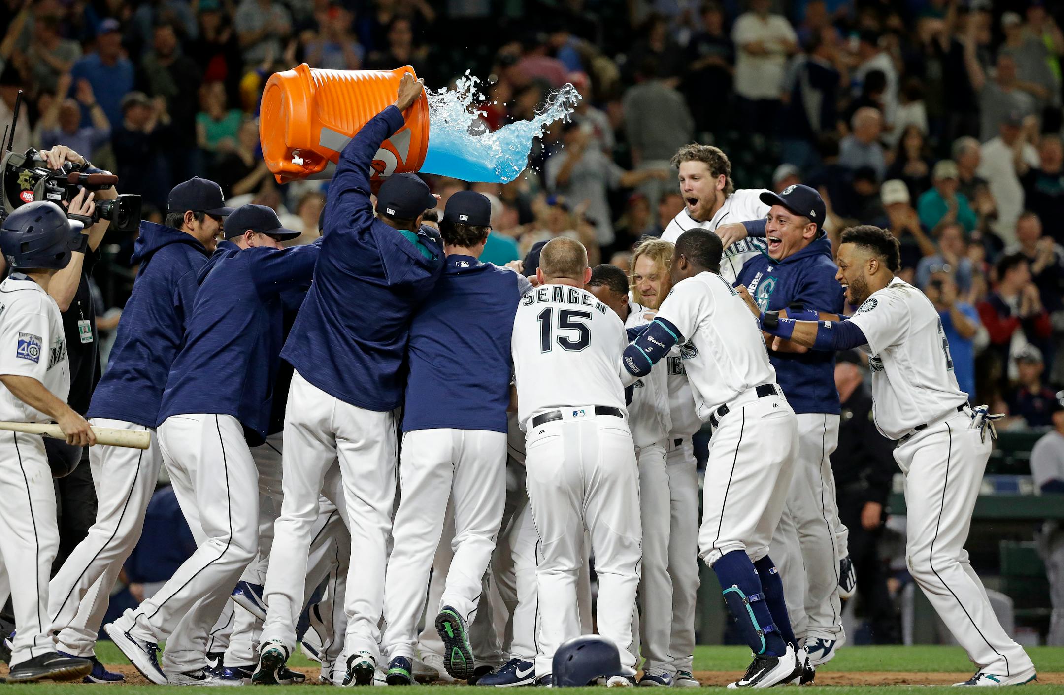 Seattle Mariners players surround Mike Zunino and tip a giant container of sports drink over the crowd after his two-run home run in the ninth inning gave the team a 6-5 win over the Minnesota Twins in a baseball game Wednesday, June 7, 2017, in Seattle. (AP Photo/Elaine Thompson)