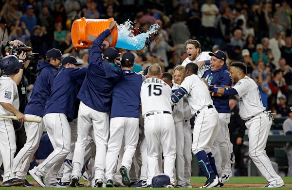 Seattle Mariners players surround Mike Zunino and tip a giant container of sports drink over the crowd after his two-run home run in the ninth inning 