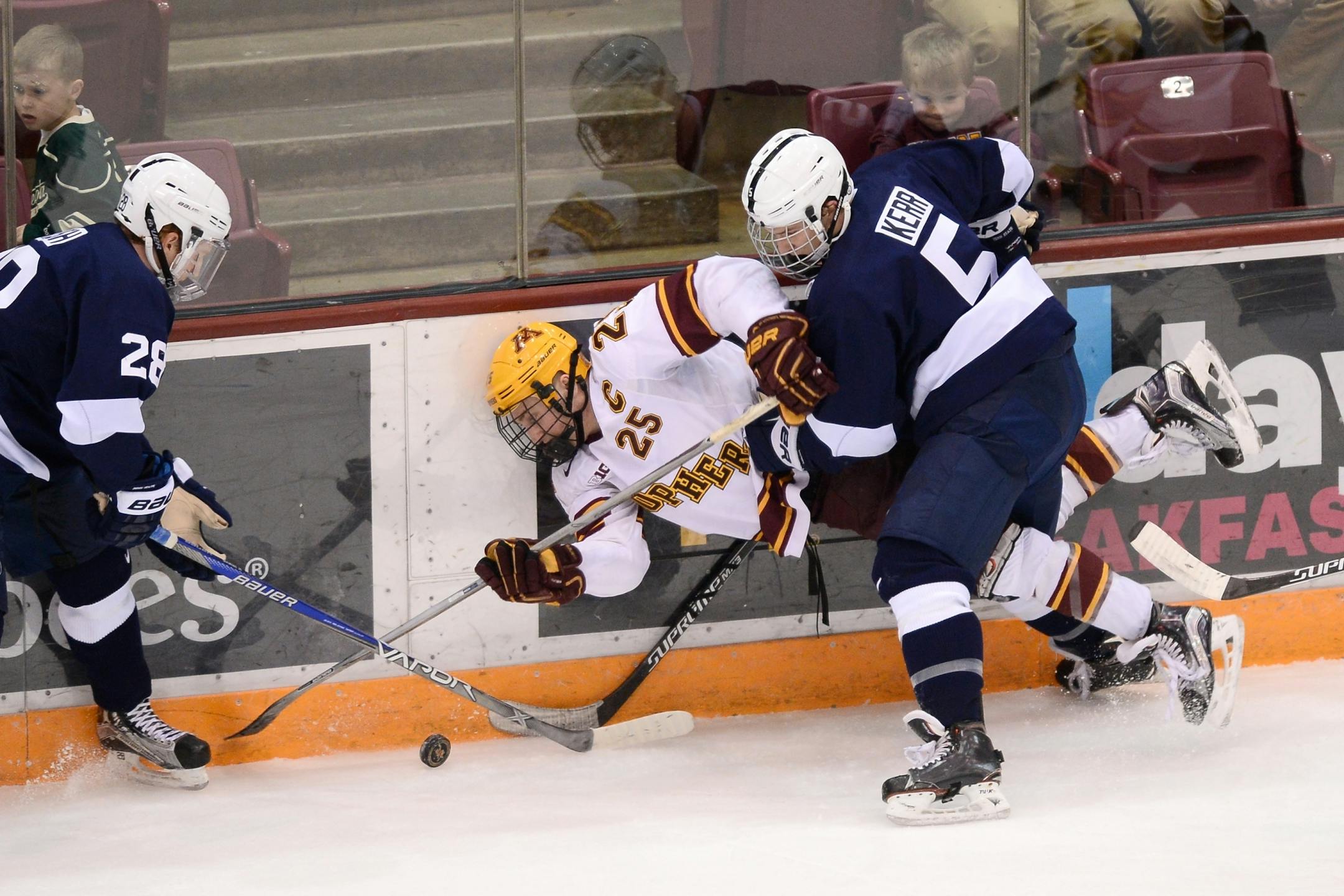 Minnesota Golden Gophers center Justin Kloos (25) fell to the ice while going after the puck being defended by Penn State Nittany Lions forward Alec Marsh (28) and defenseman Kevin Kerr (5) in the first period.