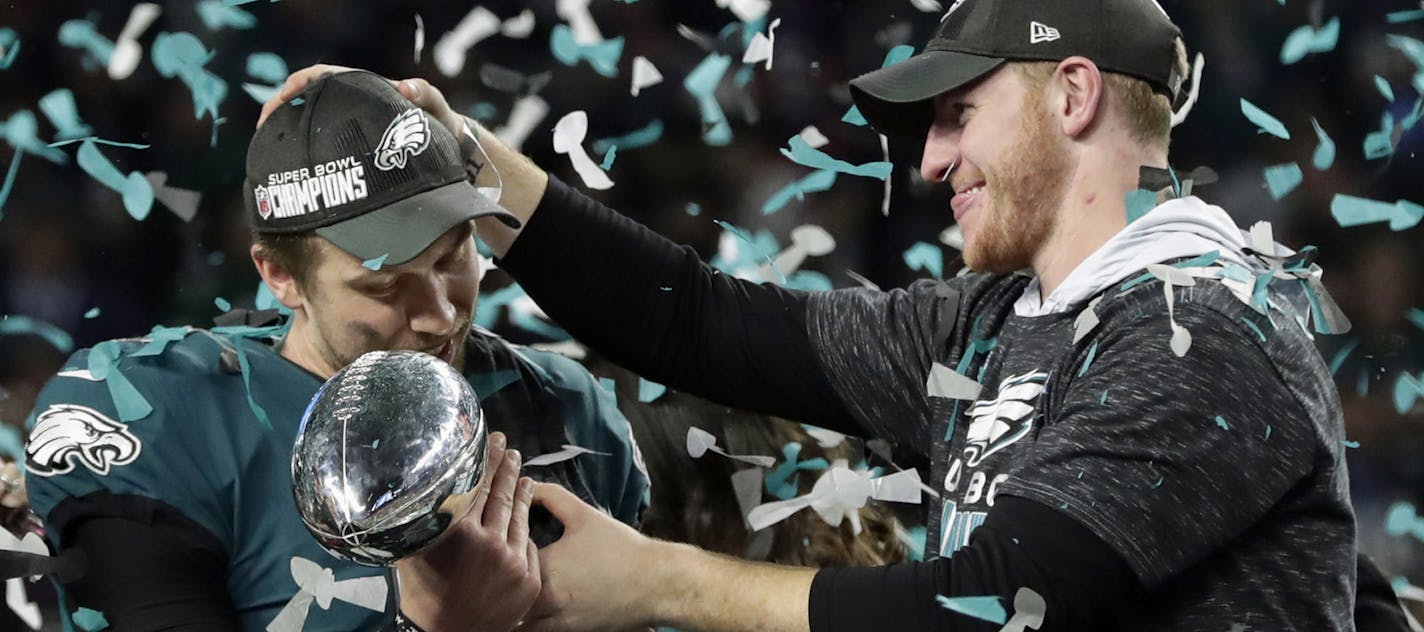 Philadelphia Eagles quarterback Carson Wentz, right, hands the Vincent Lombardi trophy to Nick Foles after winning the NFL Super Bowl 52 football game against the New England Patriots, Sunday, Feb. 4, 2018, in Minneapolis. The Eagles won 41-33. (AP Photo/Frank Franklin II)