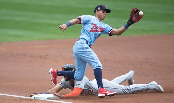 Detroit Tigers center fielder Victor Reyes (22) was safe on a play at third , as Twins third baseman Ehire Adrianza (13) caught the ball in the first 