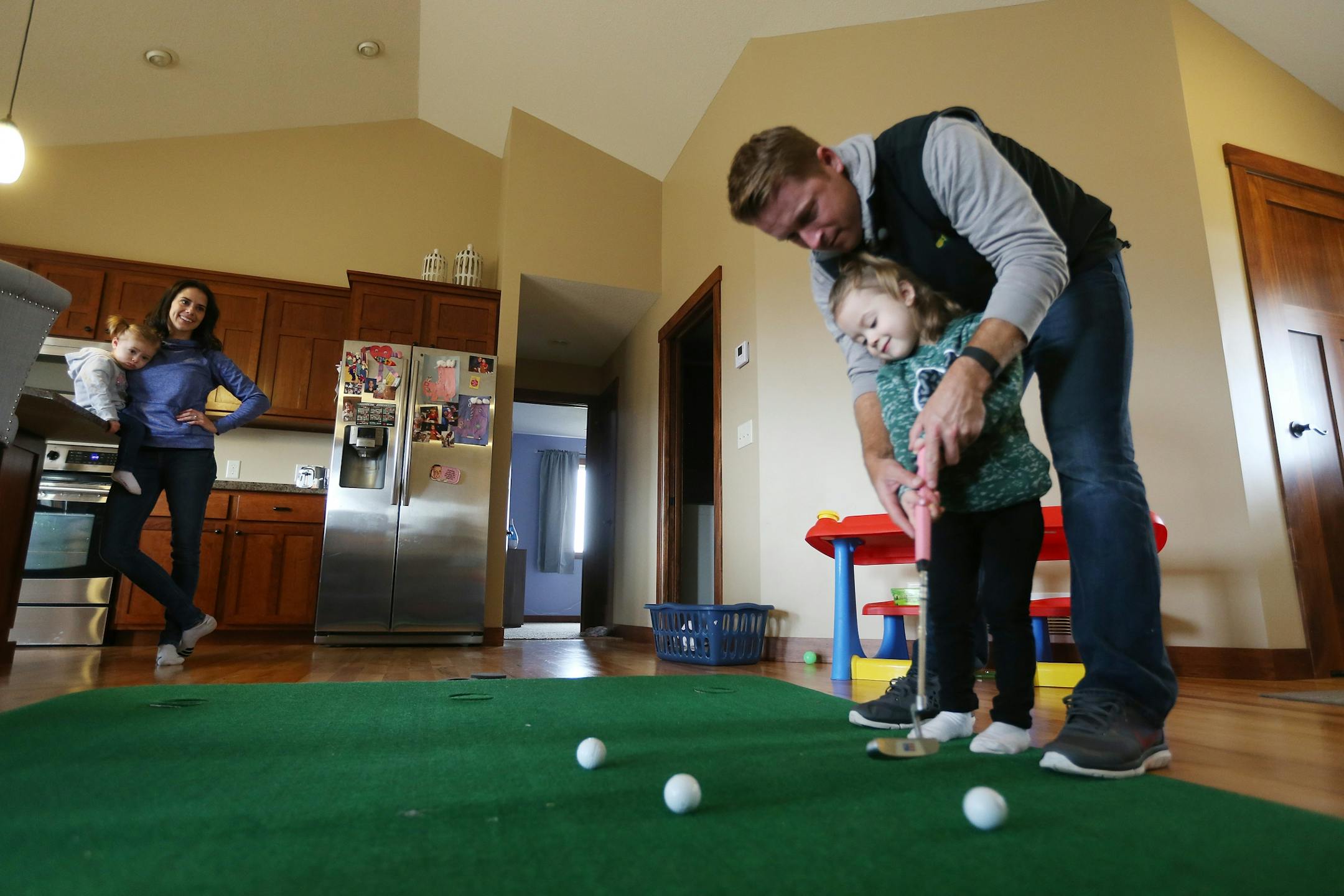 Sammy Schmitz putted with his daughter Aubree 3, and his wife Natalie and younger daughter Allie 1 looking on at their house in River Falls, Wis.
