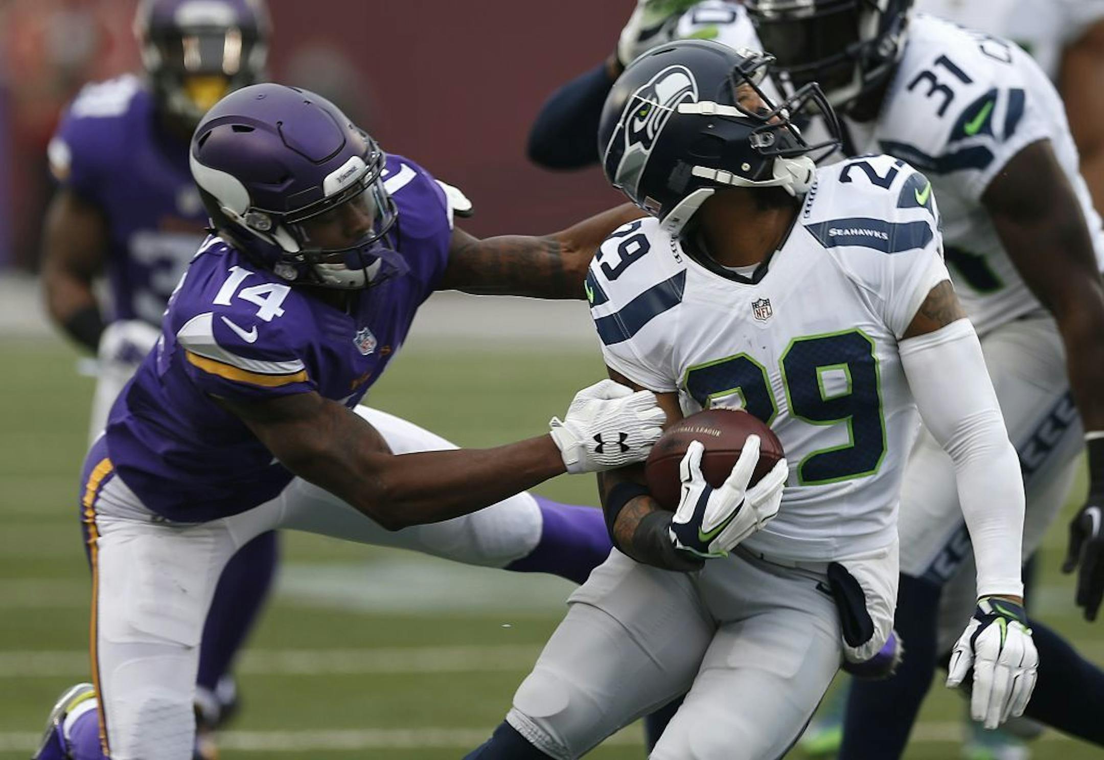 Seattle Seahawks free safety Earl Thomas (29) has his helmet turned a face mask by Minnesota Vikings wide receiver Stefon Diggs (14) while returning a interception in the first half of an NFL football game Sunday, Dec. 6, 2015 in Minneapolis.