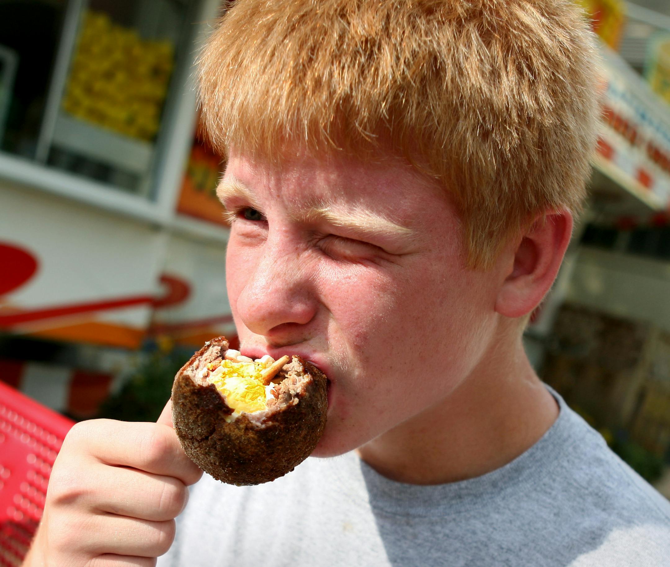 Jacob Johnson, 16, of Clearwater and his family make their first food stop, according to tradition, at the Scotch Eggs stand at the Minnesota State Fair August 25, 2013. Though a server recommended maple syrup for dipping, he stuck with his favorite--honey mustard. (Courtney Perry/Special to the Star Tribune)