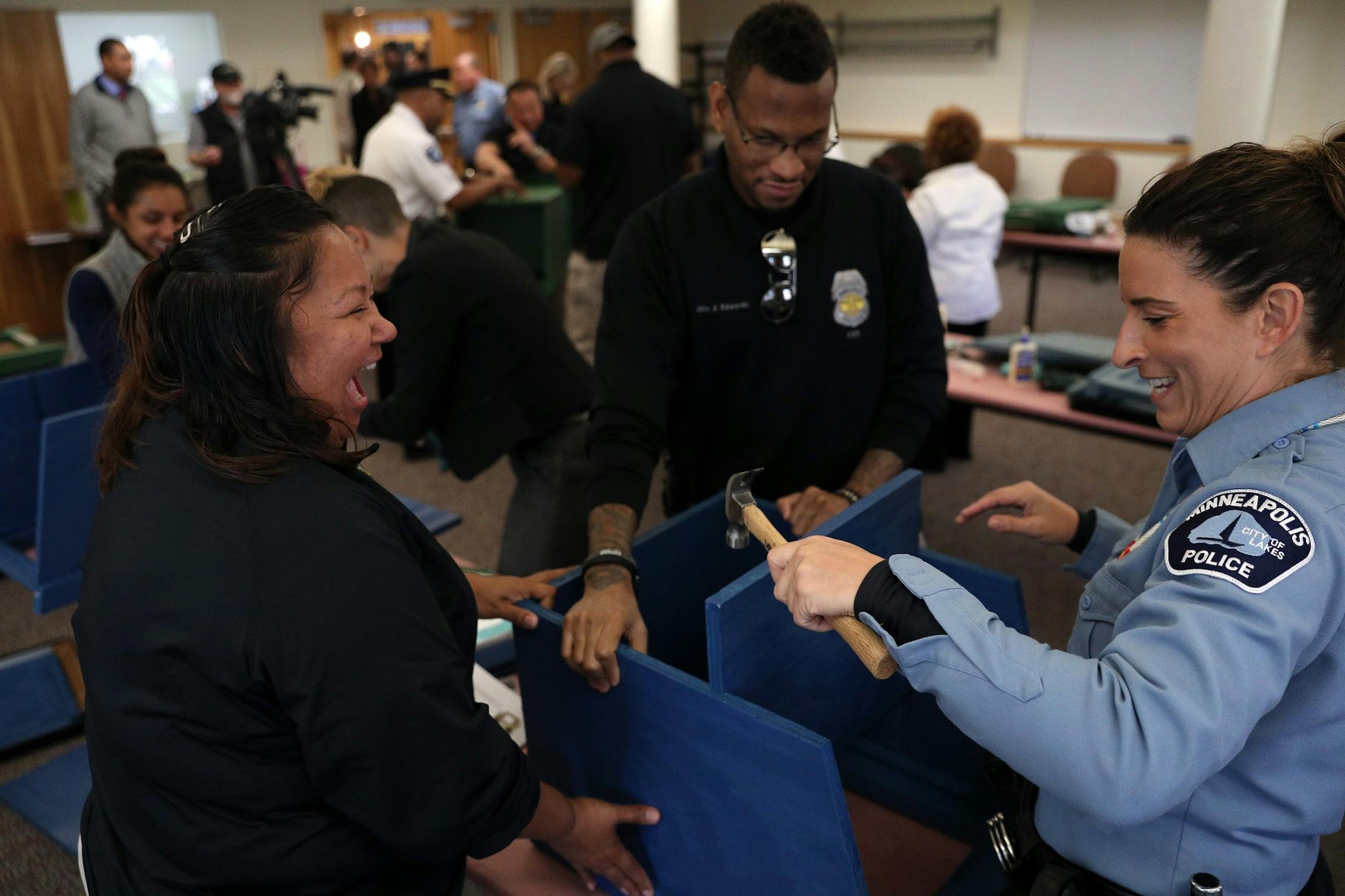 Police officers Colleen Saunby, right, Cheryl Goodman, left, and Jon Edwards, center, worked to build free-standing Little Free Libraries Tuesday.