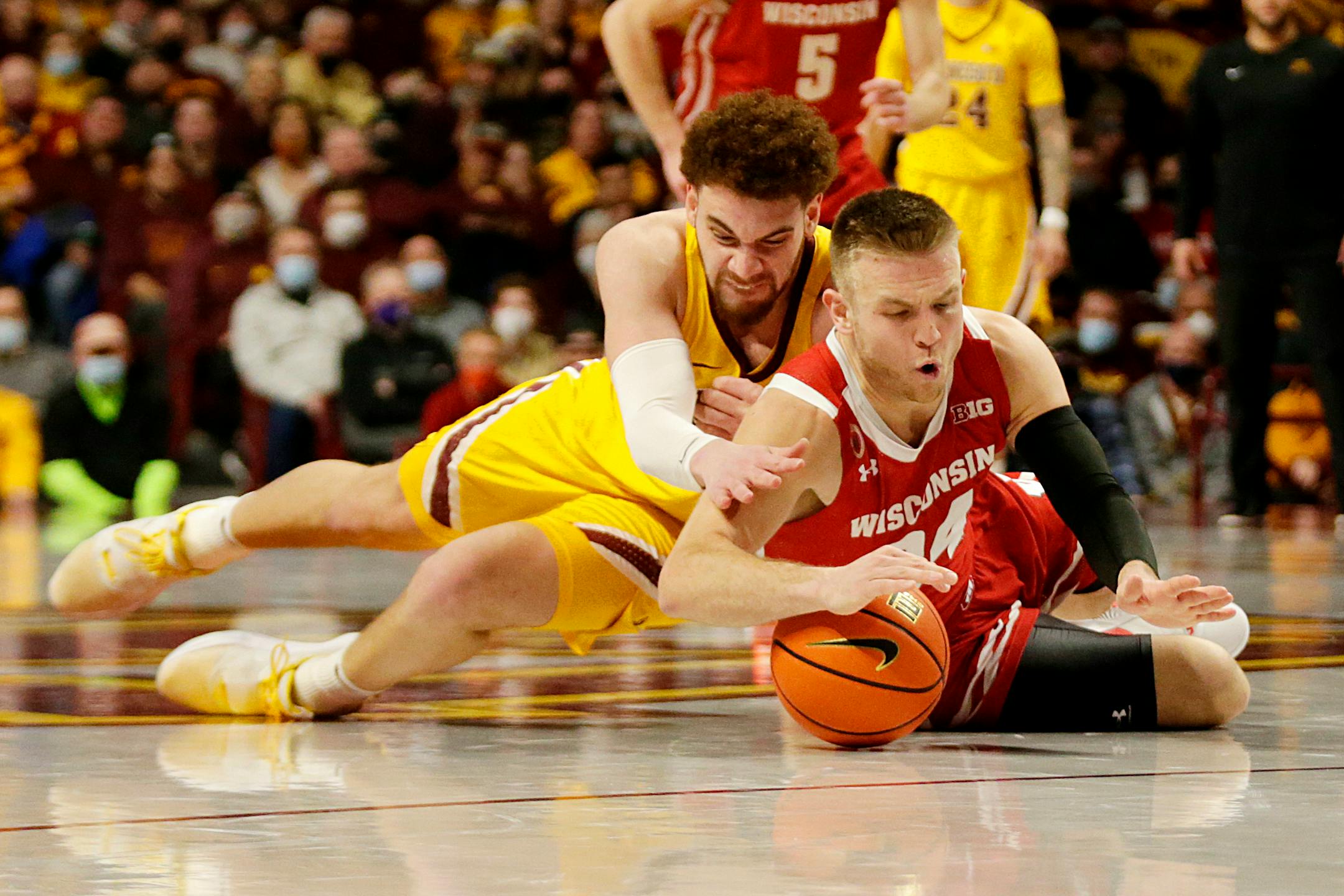 Wisconsin guard Brad Davison and Gophers forward Jamison Battle dive for the ball during the second half Wednesday at Williams Arena.