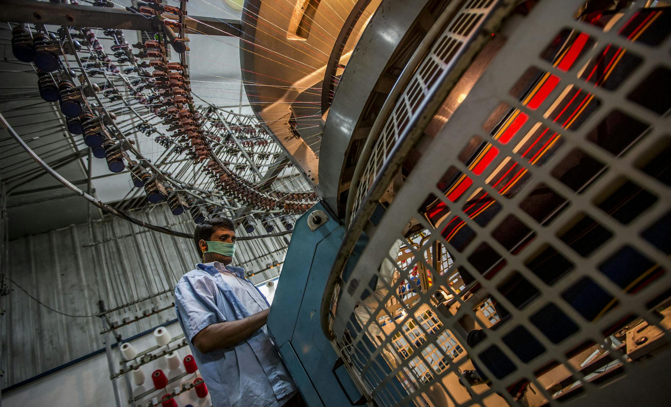 A worker operates a circular knitting machine at the Viyellatex Group garment factory in Gazipur, Bangladesh, on Thursday, May 30, 2013. Raising the billions of dollars needed to improve safety in Bangladesh's factories would entail a per-garment cost roughly equivalent to New York's subway fare in the 1960s. Photographer: Jeff Holt/Bloomberg ORG XMIT: 170183896