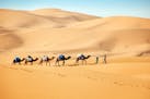 Camel herders in Morocco cross the Erg Chebbi dunes, a sweeping sea of sand reaching skyscraper heights in some places. (Norma Meyer/Los Angeles Times