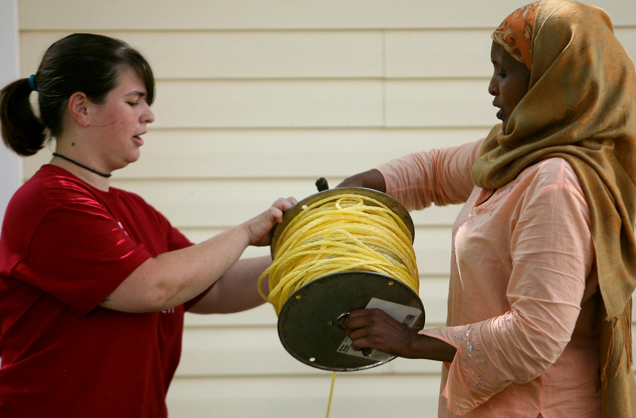 Kate Stalnaker , left, helped homeowner Sadia Noor role up rope at her home.