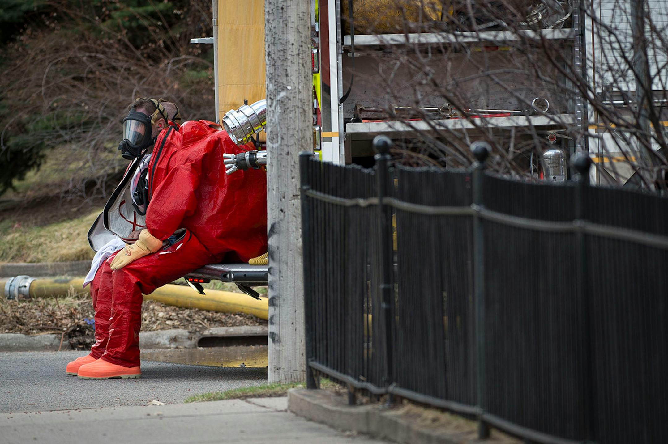 A firefighter donning a hazardous material suit rests on the back of a fire truck after investigating a residency involved in a chemical scare on Friday afternoon in the Marcy Holmes neighborhood.