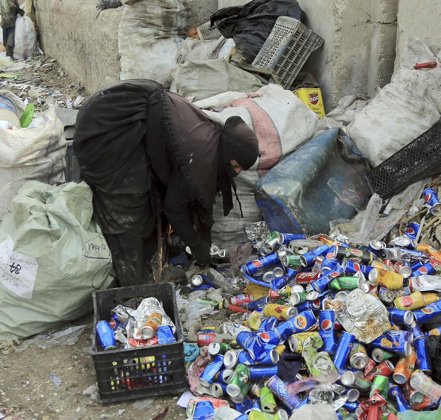 Um Abdullah, who lost her husband in a car bomb explosion, collects recyclable items at a garbage dump to support her family in Baghdad, Iraq, Thursday, March 3, 2016. Most workers in the garbage dump are widows orphans who live below the poverty line. (AP Photo/Karim Kadim) ORG XMIT: MIN2016032416363642