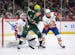 Wild center Joel Eriksson Ek (14) looked to deflect an incoming puck while fighting for position with New York Islanders defenseman Ryan Pulock (6) in