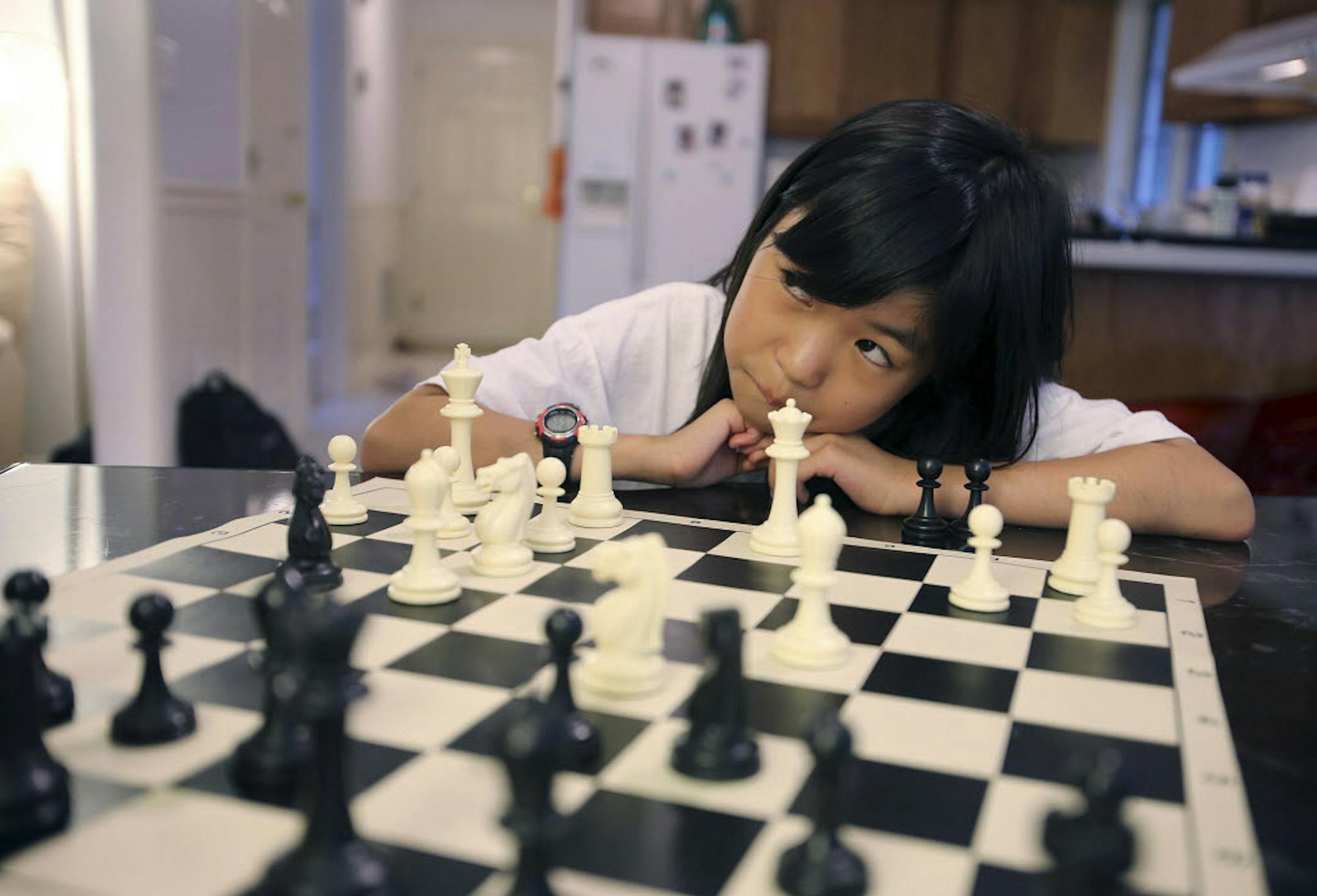 Carissa Yip, 9, waits for her father Percy Yip to make a move during a chess match at their home in Chelmsford, Mass.