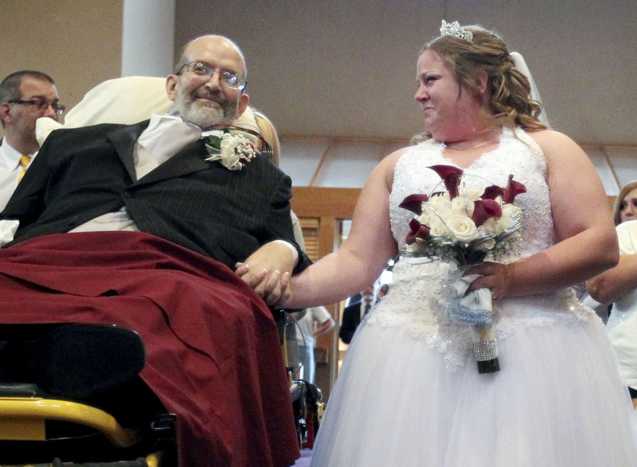 Bride Sarah Nagy, right, begins to cry as she is escorted by her father, Scott, down the aisle during her wedding ceremony Oct. 12, 2013 at First Lutheran Church in Strongsville. University Hospital sent a medical team along with Scott who is bound to his bed and the ambulance ride to the church was donated by Physicians Medical Transport. (AP Photo/The Plain Dealer, John Kuntz)