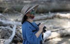 CORRECTS TO MAY 17 NOT MAY 16 - A birdwatcher wears a face mask while looking for birds at Barr Lake State Park, Sunday, May 17, 2020, near Brighton, 