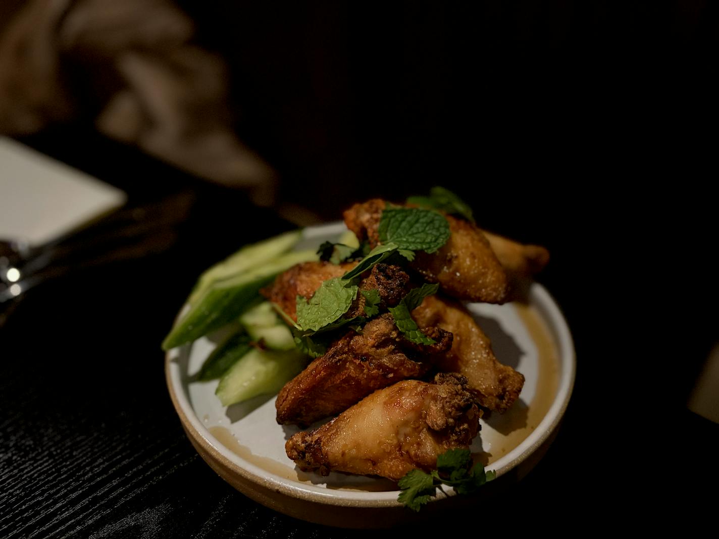 Fried wings served with cilantro and cucumber sticks.