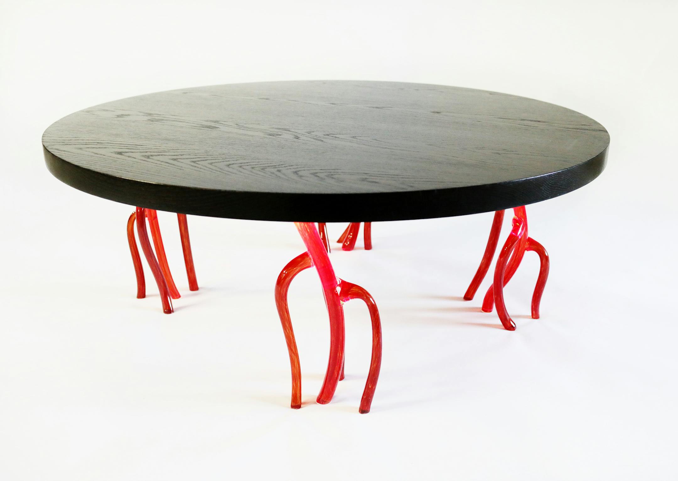 A coral cocktail table made of white oak with ebony stain and handmade glass legs, illuminated by battery power, at Willette's shop.