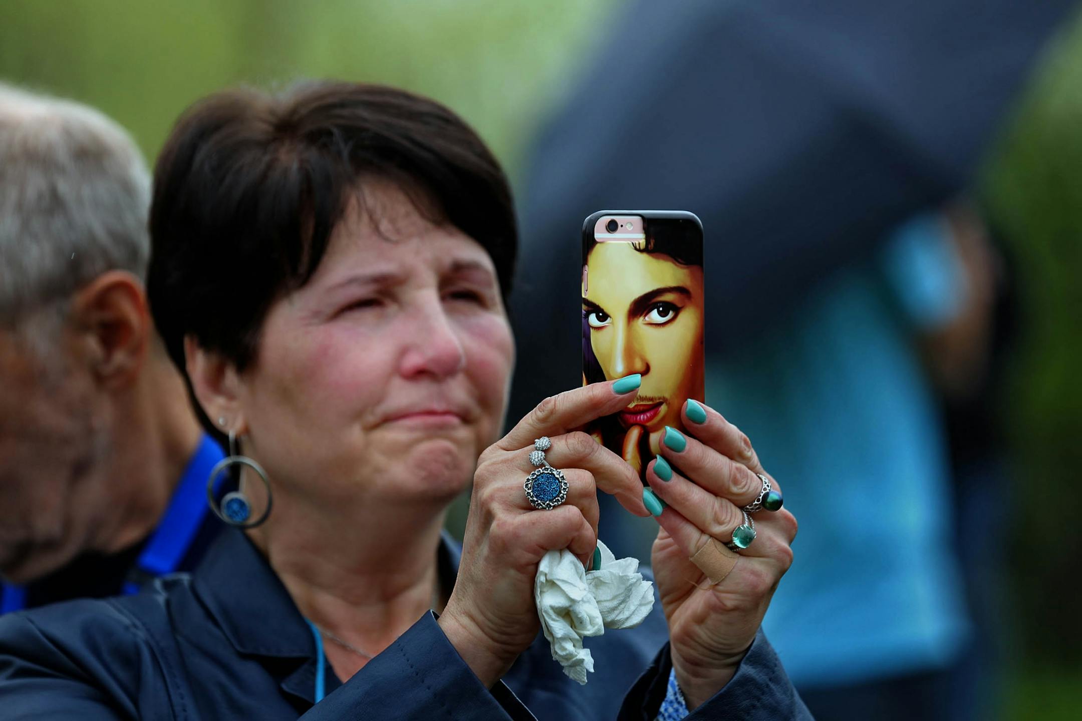 Marianna Miller held a cellphone with a picture of Prince as she and Gary Laughlin stood outside in the rain .