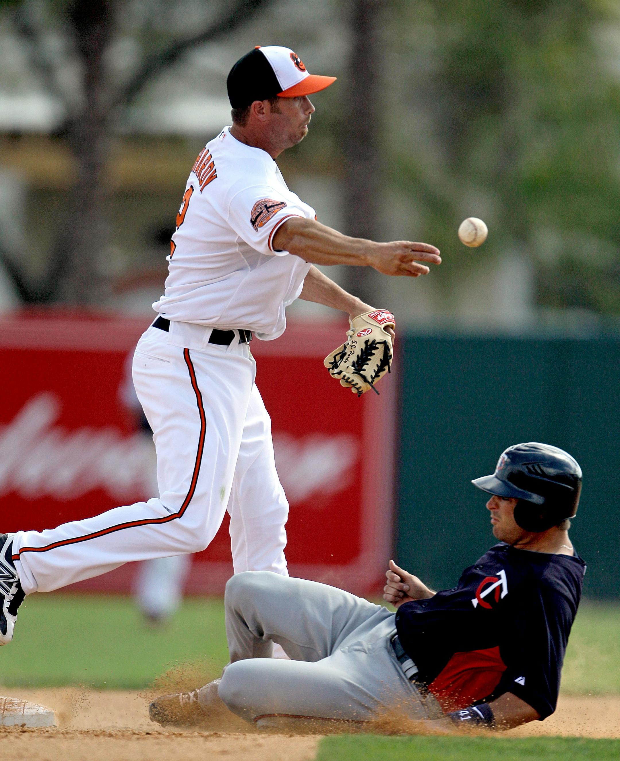 Minnesota Twins' Drew Butera, right, is out at second base as Baltimore Orioles shortstop J.J. Hardy throws to first during the fifth inning of a spring training baseball game on Wednesday, March 7, 2012, in Sarasota, Fla. Baltimore won 6-0. (AP Photo/David Goldman)