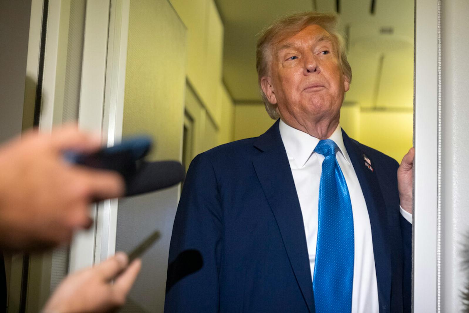President Donald Trump speaks with reporters Monday while flying aboard Air Force One en route from Calgary to Joint Base Andrews, Md.