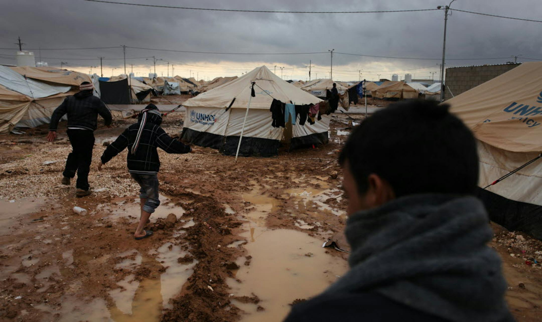 Syrian refugees face squalid conditions, made worse lately by a winter storm. At the Zaatari camp, above, refugees made their way through mud. Frustrated after their tents collapsed in high winds, some refugees in the Jordanian camp attacked aid workers with sticks and stones.